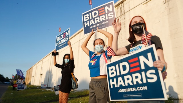Joud Elsherbiny, Jana E., and Heather McCluskie wave their Biden-Harris signs at the Town 'N Country Regional Public Library on November 3, 2020 in Tampa, Florida.
