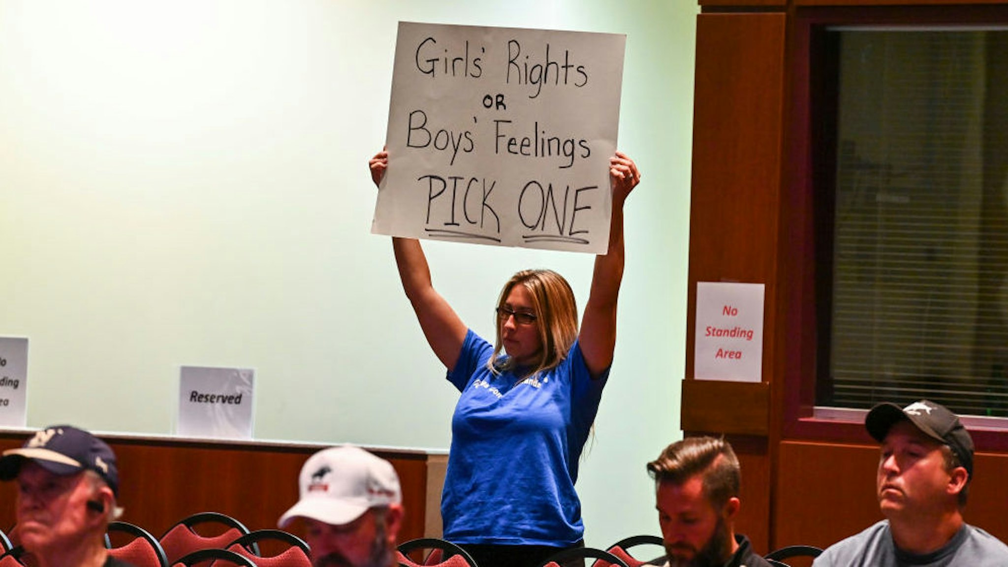 A woman holds a sign as Loudoun County School Board members vote to enact Policy 8040 during a school board meeting at the Loudoun County Public Schools Administration Building on August 11, 2021 in Ashburn, Va.