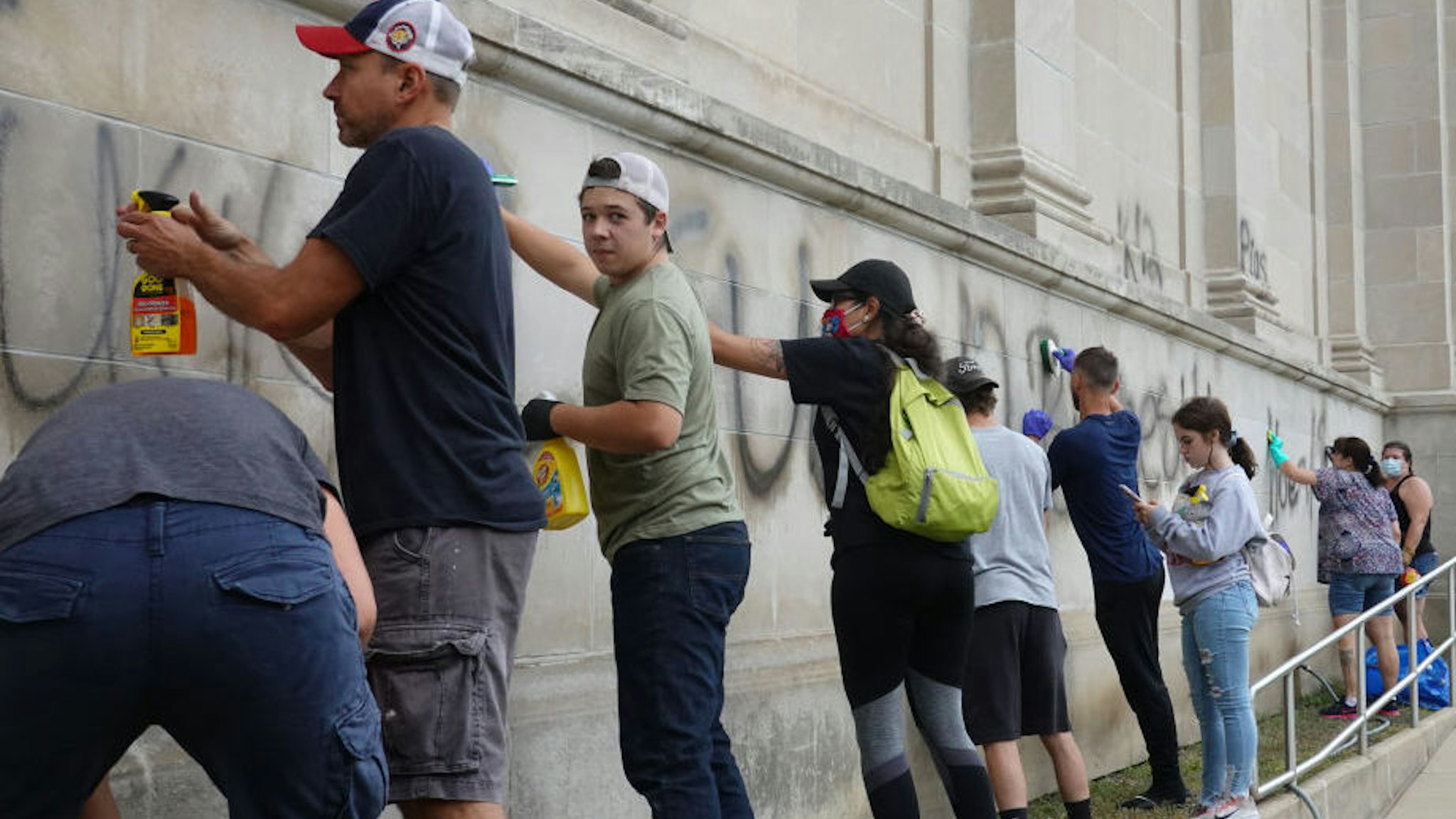 Volunteers clean graffiti from a high school near the Kenosha County Courthouse following another night of unrest on August 25, 2020 in Kenosha, Wisconsin.