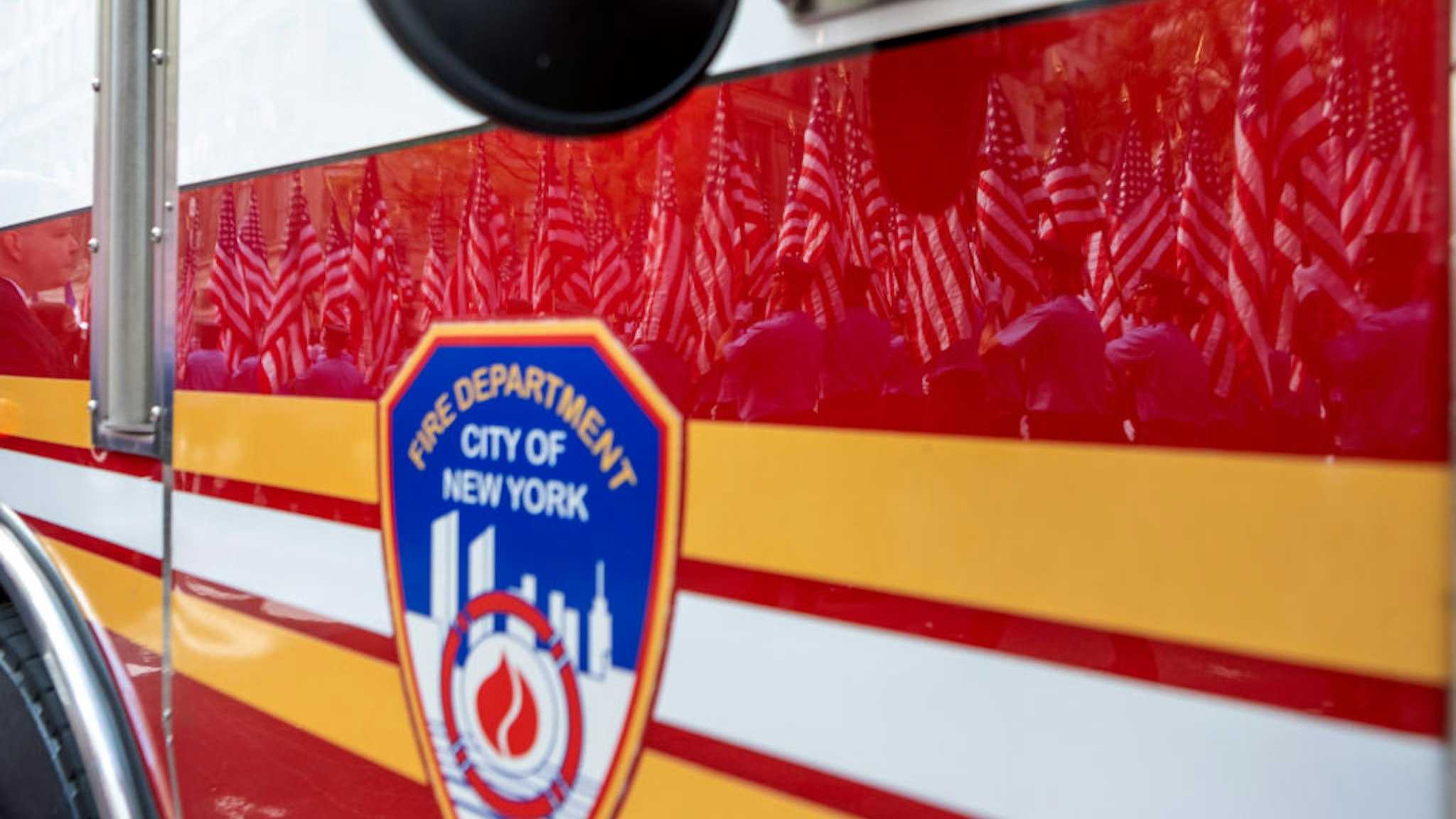 Members of the New York City Fire Department carrying American flags are reflected off a fire truck during a processional during the FDNY Memorial Service at St. Patrick's Cathedral on September 11, 2021 in New York City.