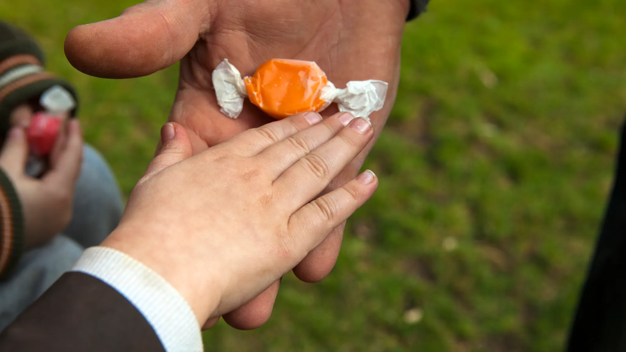 Child taking candy from an adult Child taking candy from an adult. Temptation by pedophile