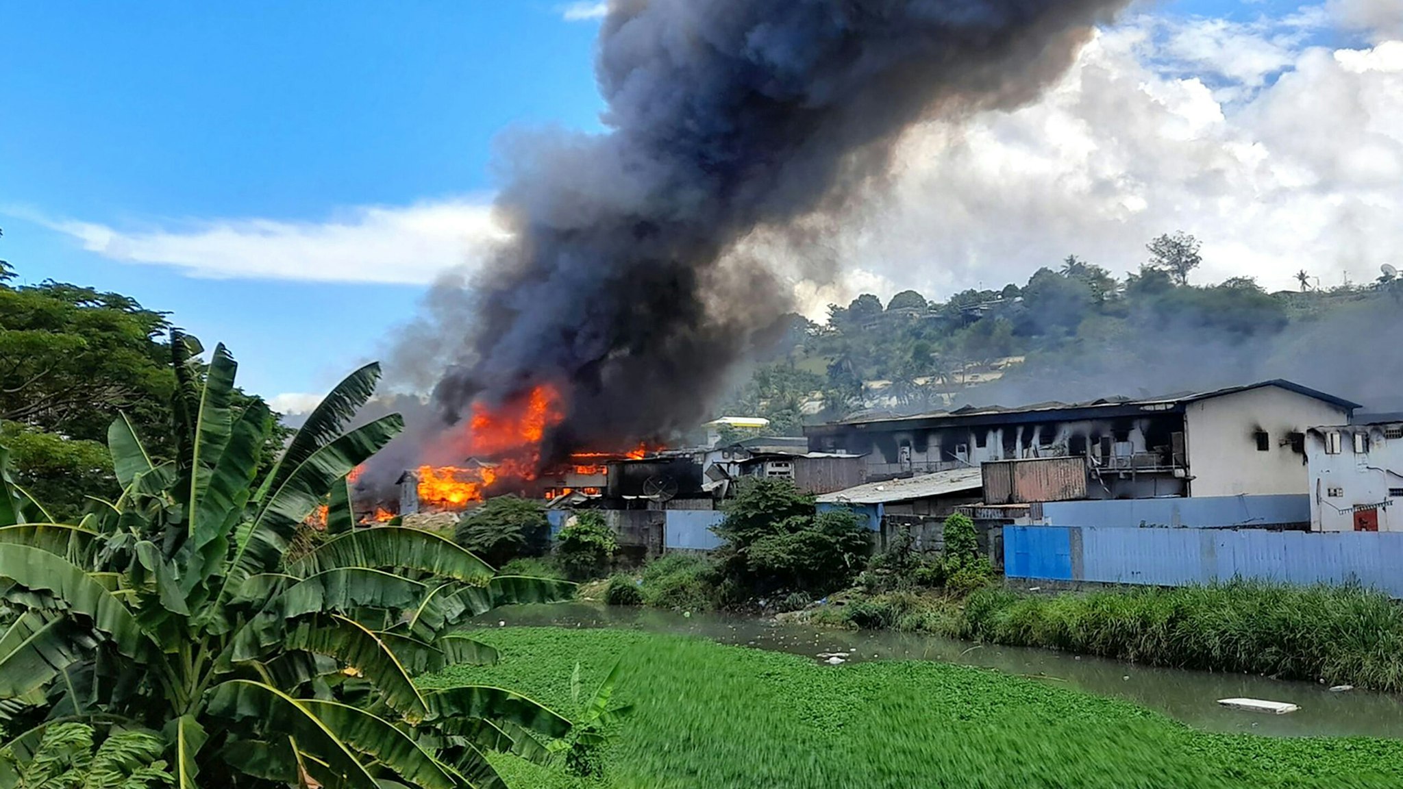Flames rise from buildings in Honiara's Chinatown on November 26, 2021 as days of rioting have seen thousands ignore a government lockdown order, torching several buildings around the Chinatown district including commercial properties and a bank branch.