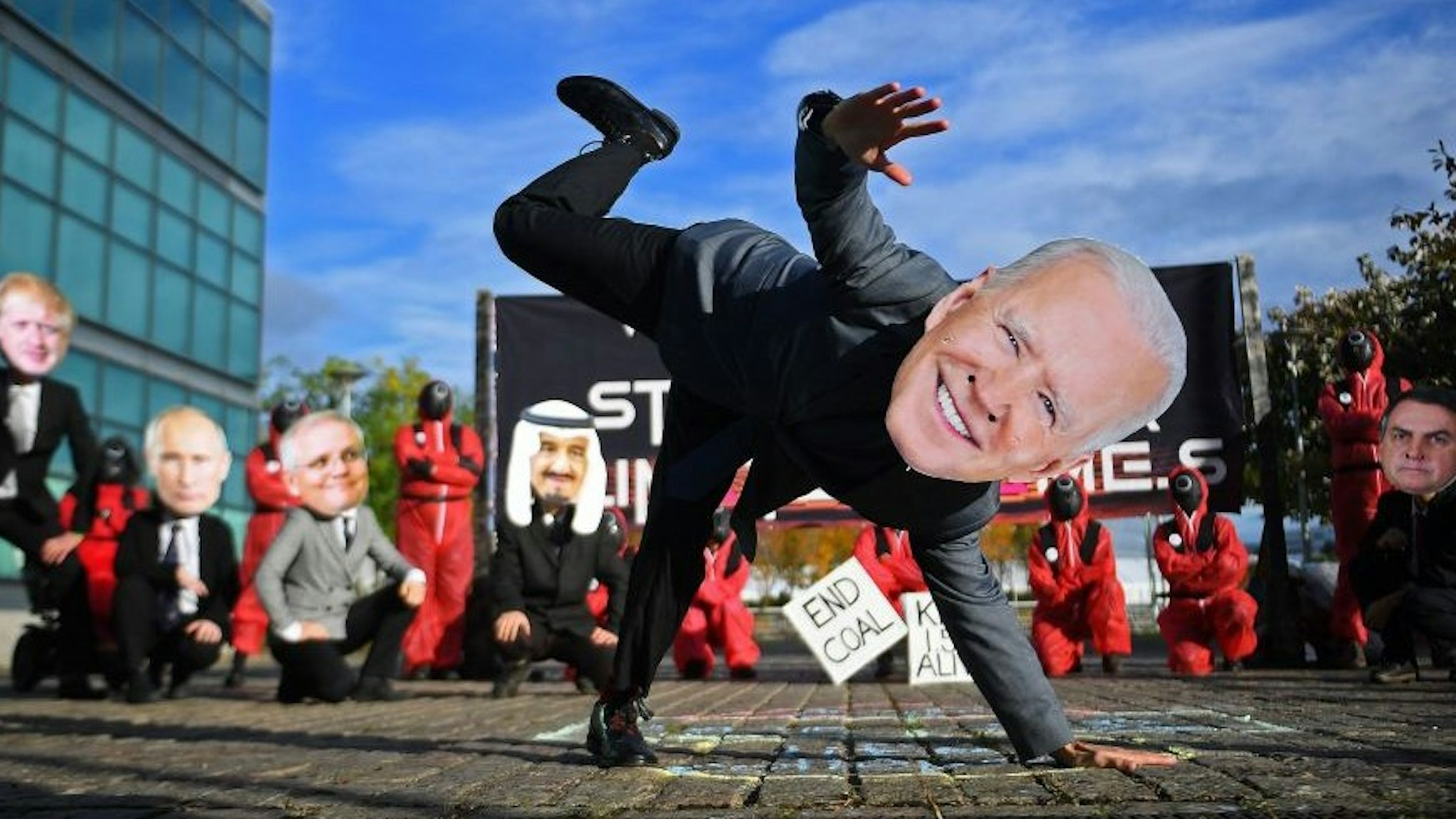 Climate change activists wearing masks depicting images of World leaders, including US President Joe Biden, take part in a "Squid Game" themed demonstration near the Scottish Event Campus (SEC), the venue of the COP26 UN Climate Change Conference in Glasgow, Scotland on November 2, 2021. - World leaders meeting at the COP26 climate summit in Glasgow will issue a multibillion-dollar pledge to end deforestation by 2030 but that date is too distant for campaigners who want action sooner to save the planet's lungs. (Photo by ANDY BUCHANAN / AFP) (Photo by