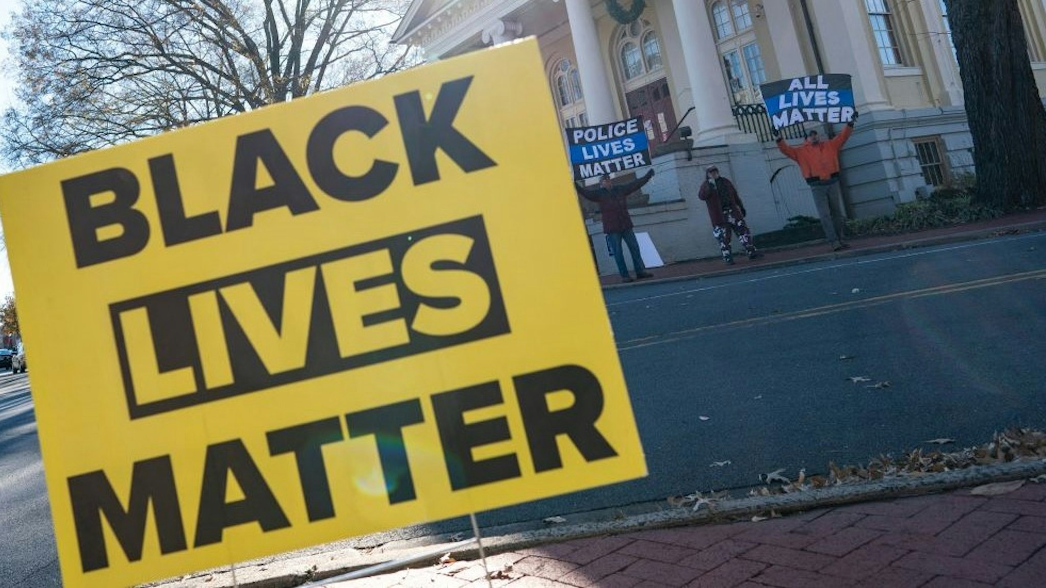 Demonstrators holding protest signs reading 'Police Lives Matter', and 'All Lives Matter' demonstrate across the street from a 'Black Lives Matter' demonstration in the town square in Warrenton, Virginia on November 27, 2021. (Photo by ALEX EDELMAN / AFP) (Photo by