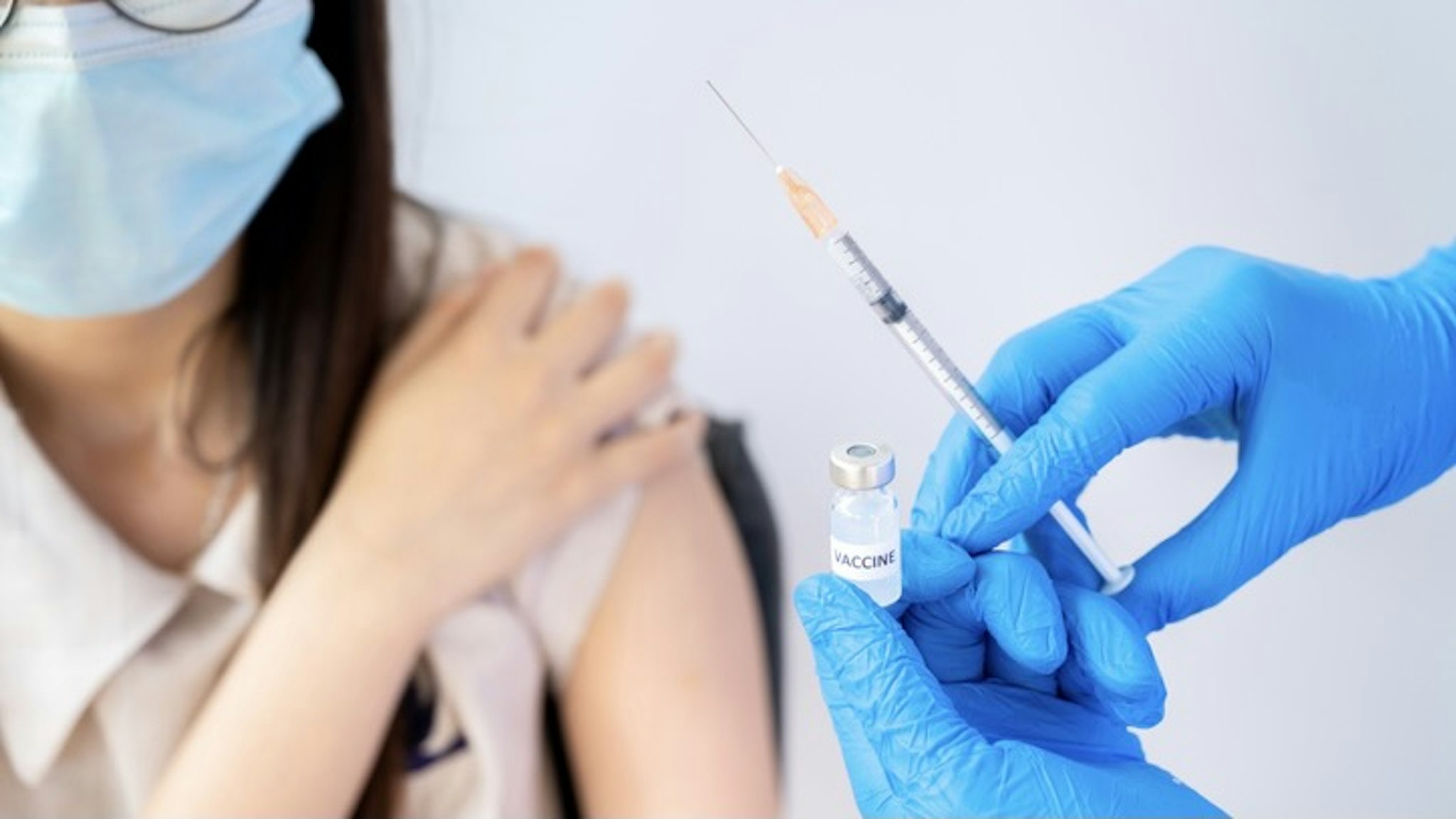Close up of doctor hands holding a bottle of covid-19 vaccine and syringe before injection to female patient. - stock photo Conceptual of vaccination and prevention against flu or virus pandemic. Boy_Anupong via Getty Images