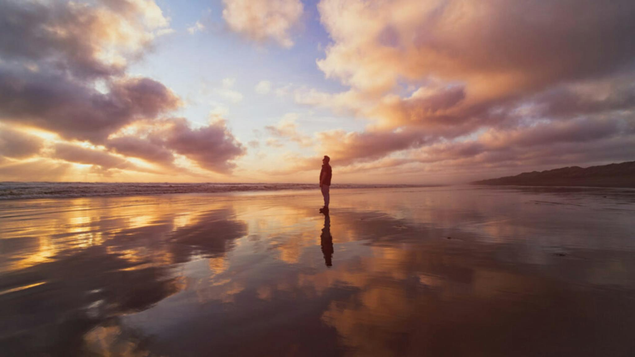 A man enjoying a beautiful sunset at Muriwai Beach, Auckland, New Zealand.