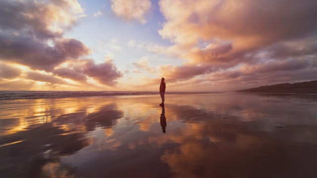 A man enjoying a beautiful sunset at Muriwai Beach, Auckland, New Zealand.