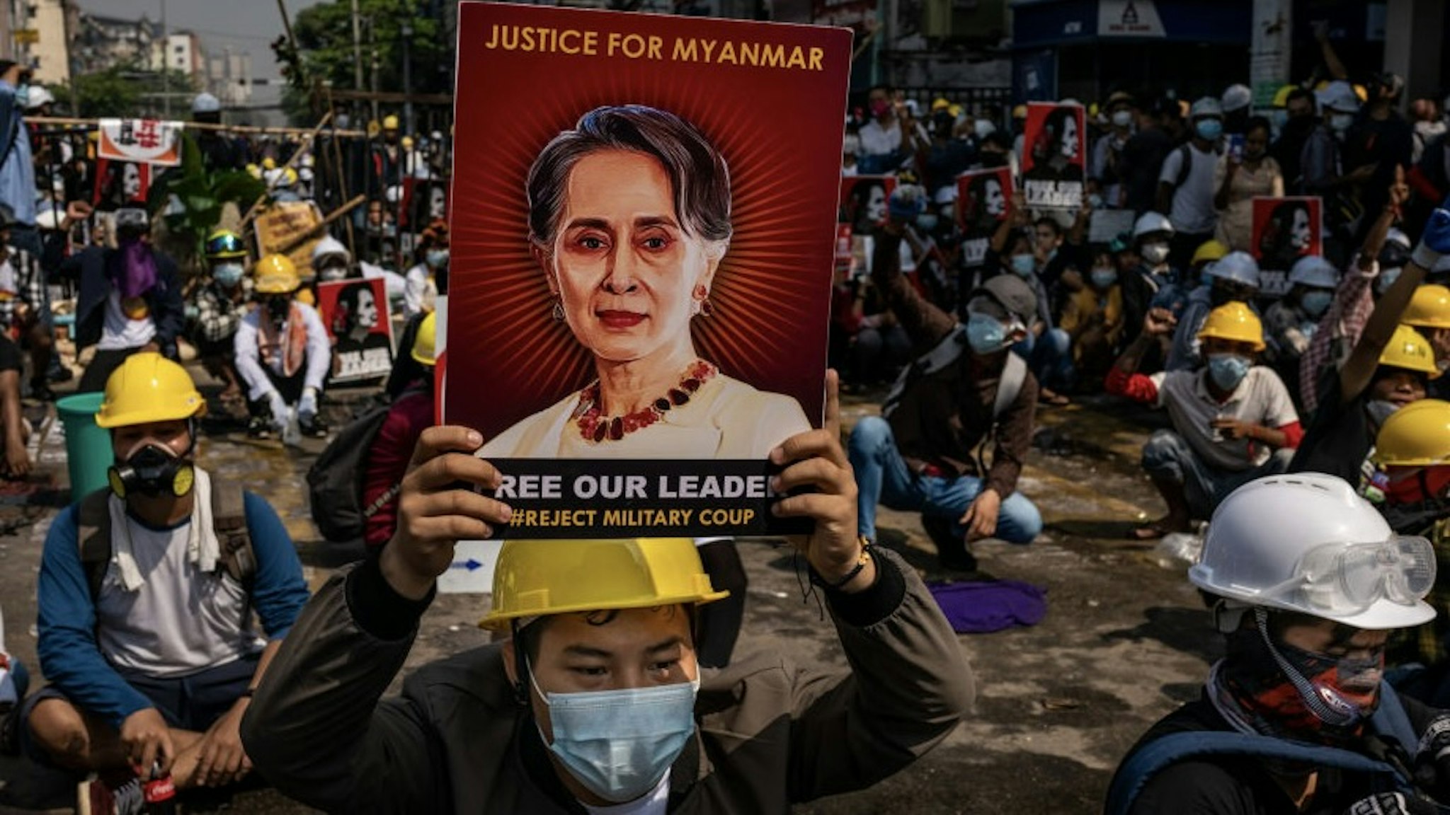 Riot Police Crack Down On Anti-coup Protesters YANGON, MYANMAR - MARCH 02: An anti-coup protester holds up a placard featuring de-facto leader Aung San Suu Kyi on March 02, 2021 in Yangon, Myanmar. Myanmar's military government has intensified a crackdown on protesters in recent days, using tear gas and live ammunition, charging at and arresting protesters and journalists. At least 18 people have been killed so far, according to monitoring organizations. (Photo by Hkun Lat/Getty Images) Hkun Lat / Stringer