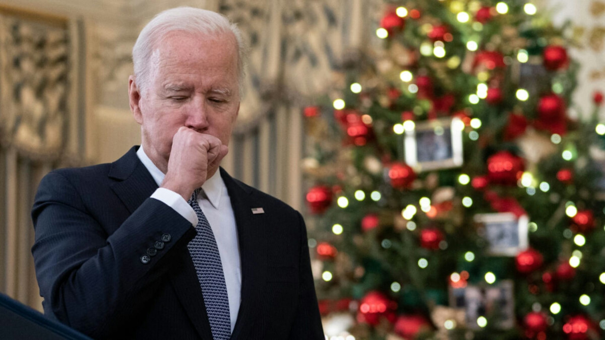 US President Joe Biden coughs as he talks to reporters about the November Jobs Report from the State Dining Room of the White House in Washington, DC, on December 3, 2021.