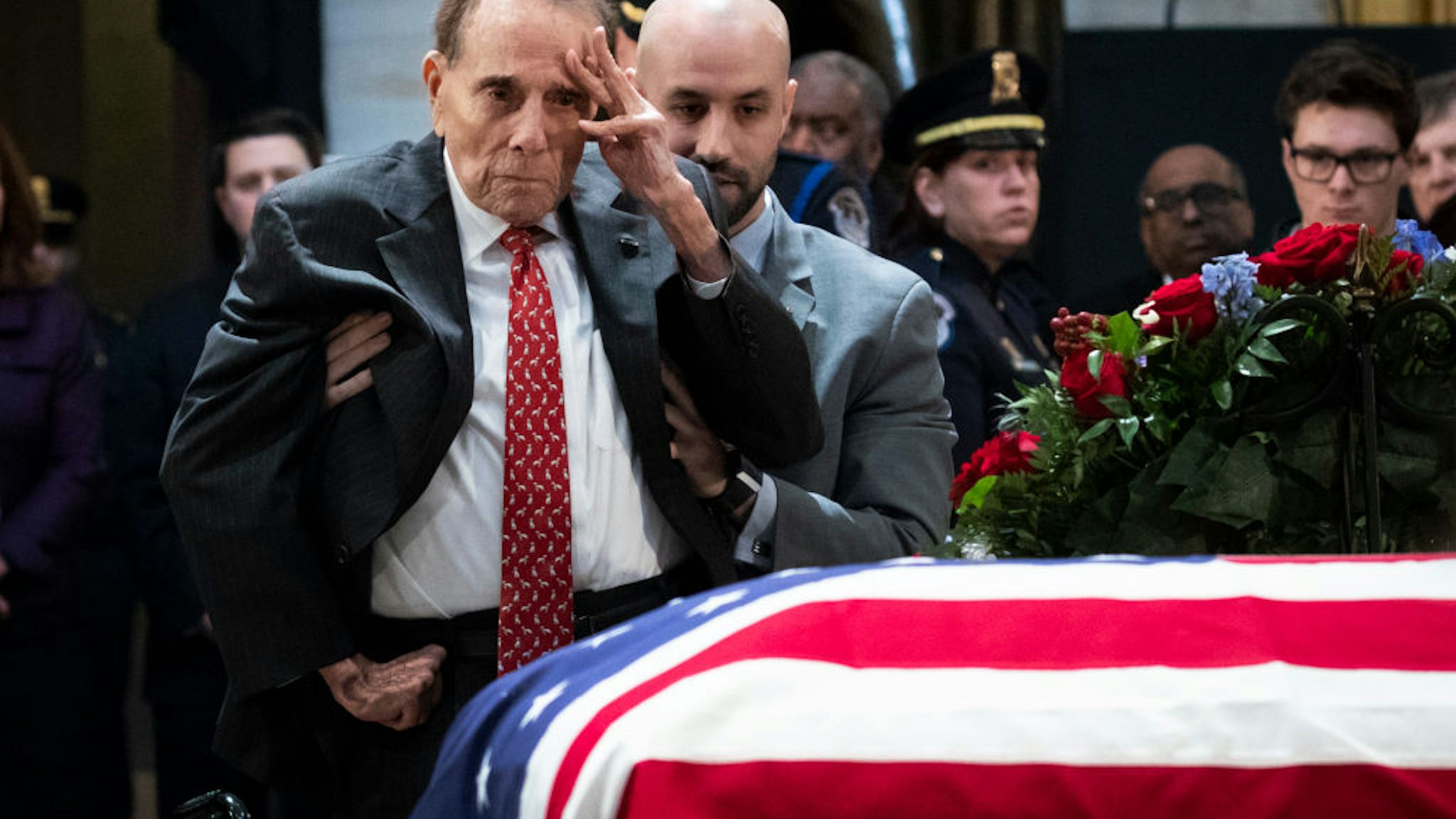WASHINGTON, DC - DECEMBER 4: Former Senator Bob Dole stands up and salutes the casket of the late former President George H.W. Bush as he lies in state at the U.S. Capitol, December 4, 2018 in Washington, DC. A WWII combat veteran, Bush served as a member of Congress from Texas, ambassador to the United Nations, director of the CIA, vice president and 41st president of the United States. Bush will lie in state in the U.S. Capitol Rotunda until Wednesday morning. (Photo by Drew Angerer/Getty Images)