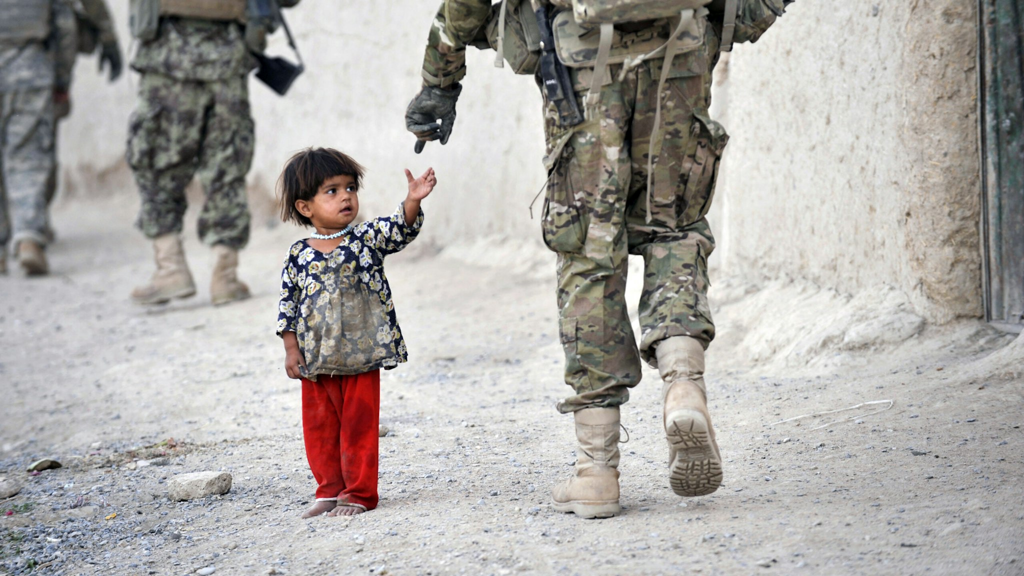 An Afghan girl greets a joint patrol of US troops from the Charlie Company, 2-87 Infantry, 3rd Brigade Combat Team and Afghan National Army soldiers at Kandalay village in the southern Afghan province of Kandahar on August 8, 2011 while US troops launched missile attacks on Taliban targets in nearby Kelawai village killing at least three and capturing two insurgents. US forces push their counterinsurgency efforts to battle for the hearts and minds of the local population. AFP PHOTO / ROMEO GACAD (Photo by Romeo GACAD / AFP) (Photo by ROMEO GACAD/AFP via Getty Images)