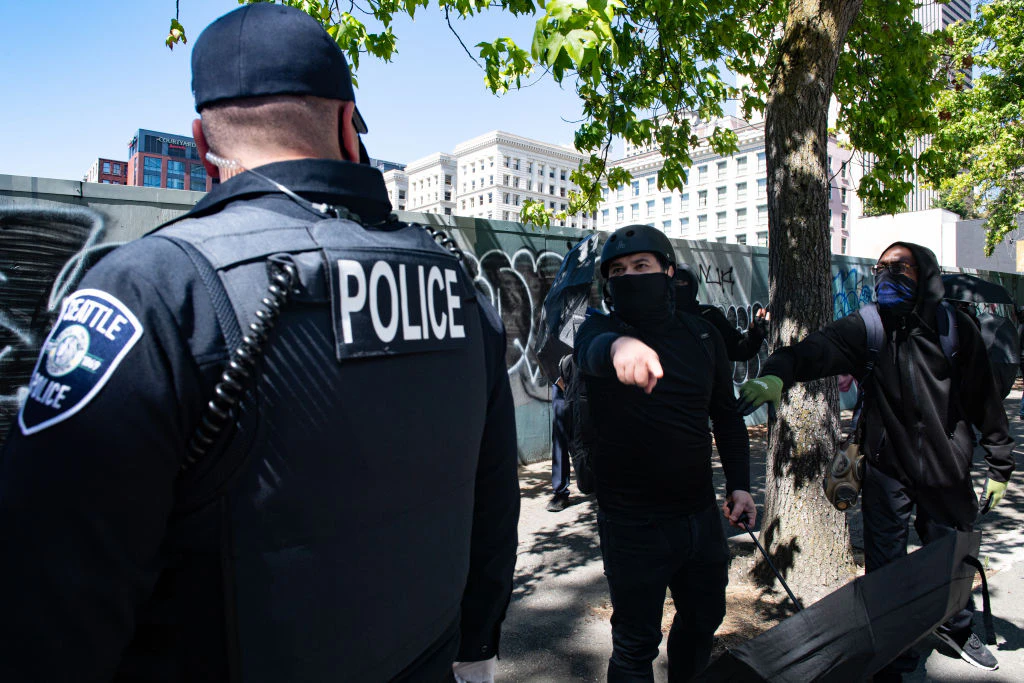 A counter protester yells a Seattle Police officer during the Seattle Police Officers Guildâs rally to stop defunding of the Seattle Police Department on Sunday, August 9, 2020 at Seattle City Hall.