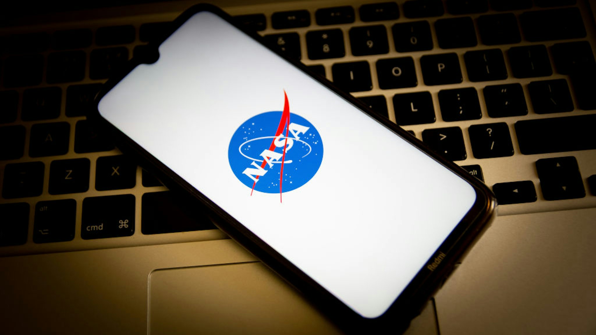 In this photo illustration, a NASA logo seen displayed on a smartphone screen with a computer keyboard in the background.