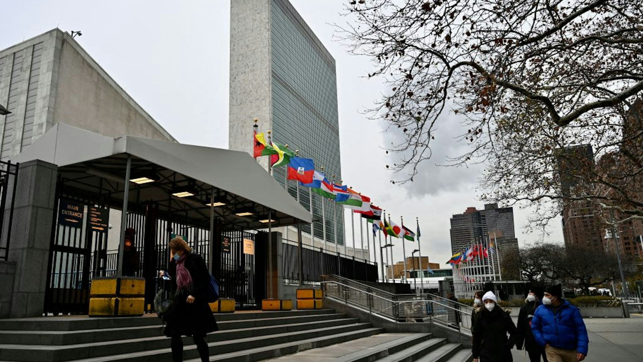 People walk in front of the United Nations Headquarters building in Manhattan, New York city, on December 8, 2021. (Photo by Daniel SLIM / AFP) (Photo by DANIEL SLIM/AFP via Getty Images)