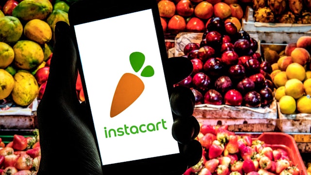 SPAIN - 2021/12/14: In this photo illustration a Instacart logo seen displayed on a smartphone with with fruits in a market in the background. (Photo Illustration by Thiago Prudencio/SOPA Images/LightRocket via Getty Images)