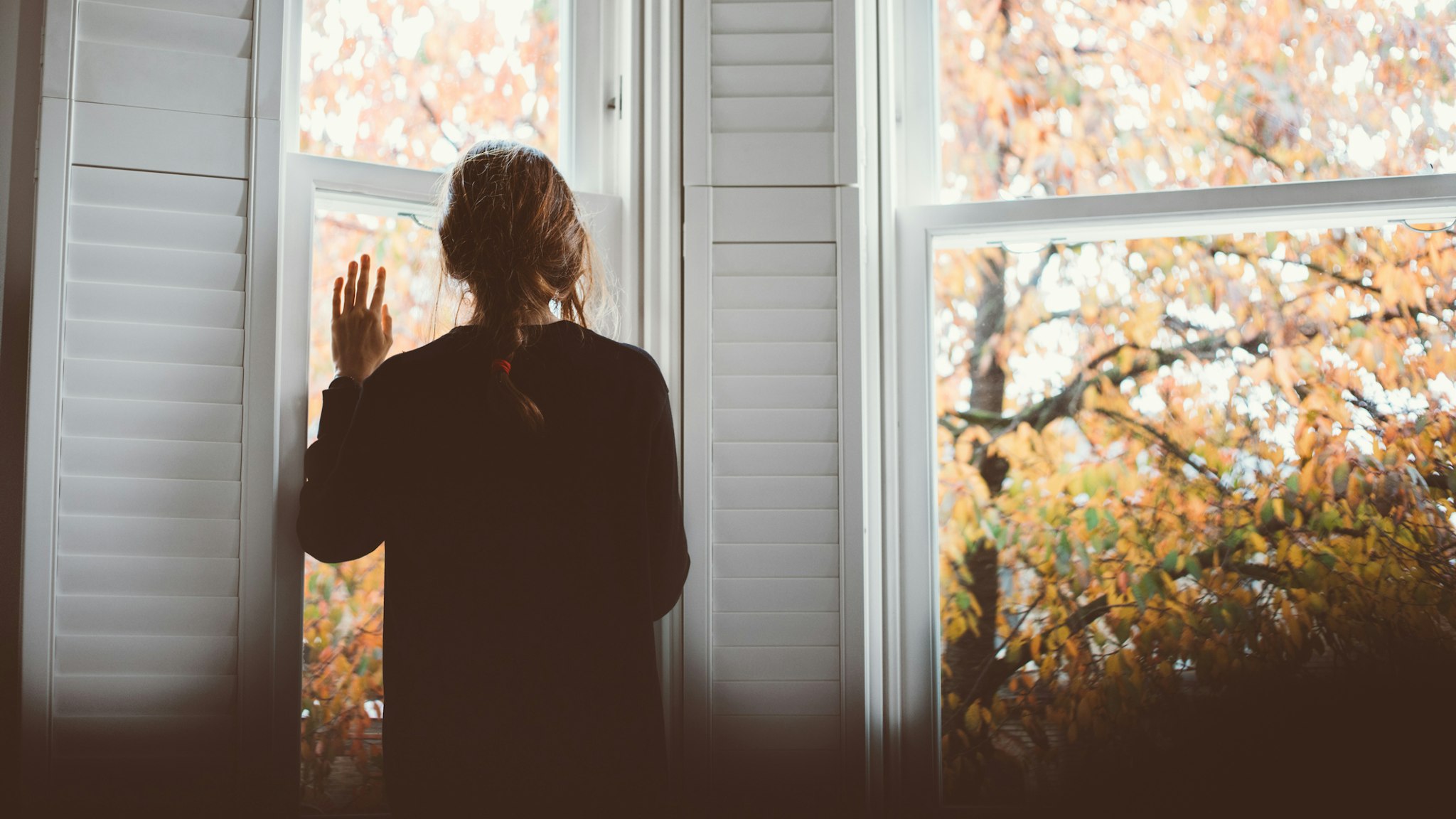 A woman looking through the window... Social distancing. - stock photo