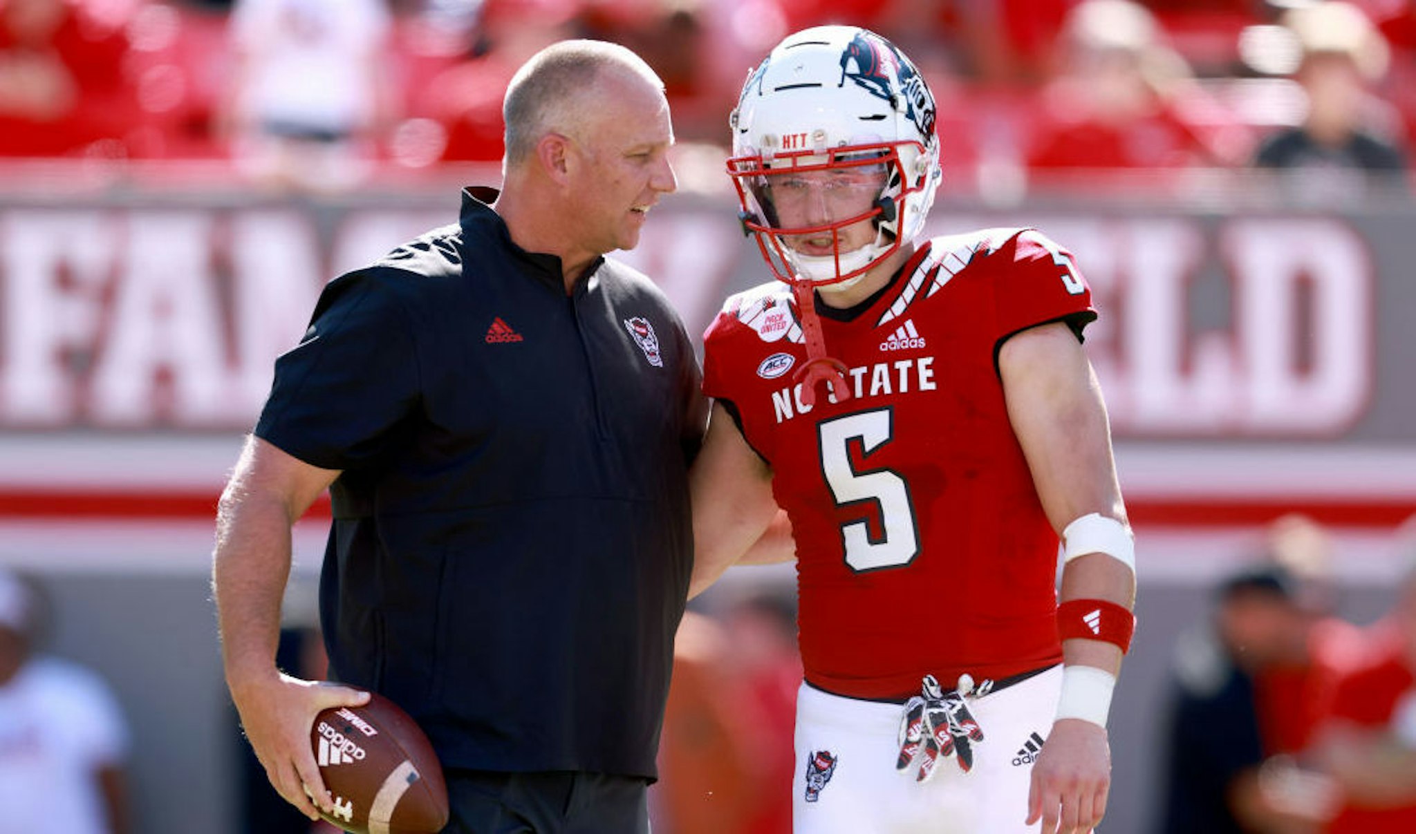 RALEIGH, NORTH CAROLINA - SEPTEMBER 25: Head coach Dave Doeren talks with Thayer Thomas #5 of the North Carolina State Wolfpack during their game against the Clemson Tigers at Carter-Finley Stadium on September 25, 2021 in Raleigh, North Carolina. North Carolina State won 27-21 in double overtime. (Photo by Grant Halverson/Getty Images)