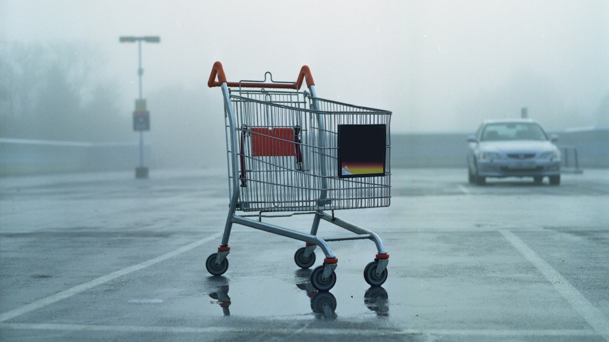 Shopping cart standing in empty parking, misty weather.