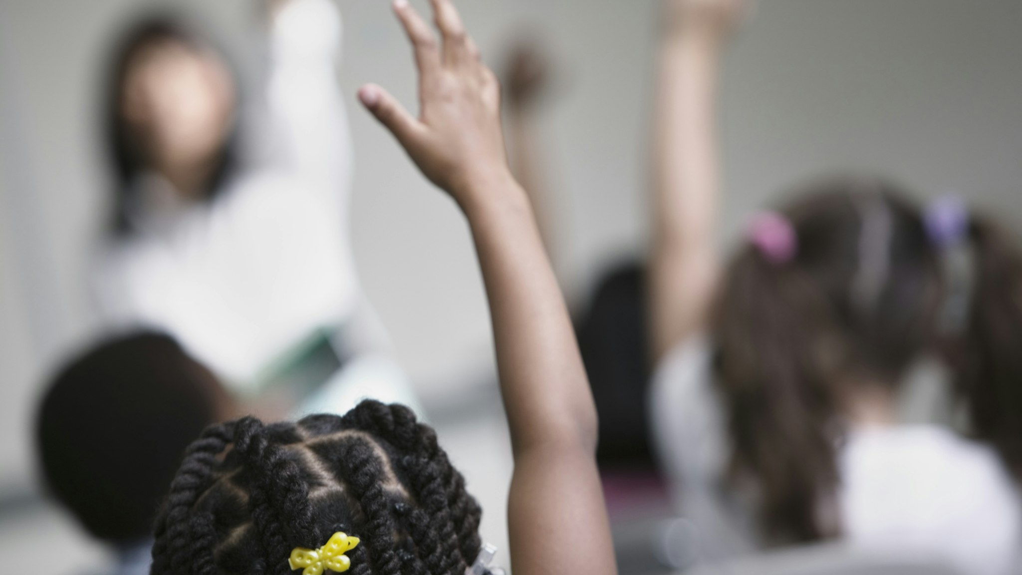 Children in class with raised hands - stock photo