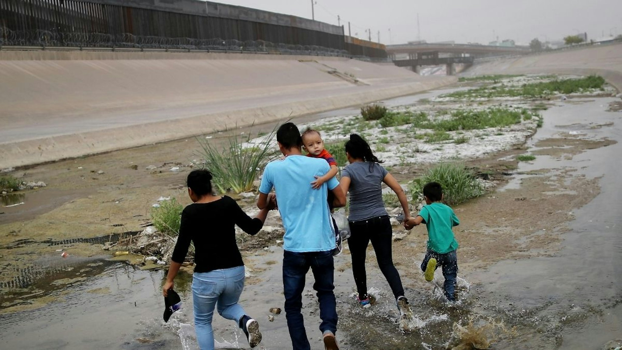Migrants hold hands as they cross the border between the U.S. and Mexico at the Rio Grande river, on their way to enter El Paso, Texas, on May 20, 2019 as taken from Ciudad Juarez, Mexico.