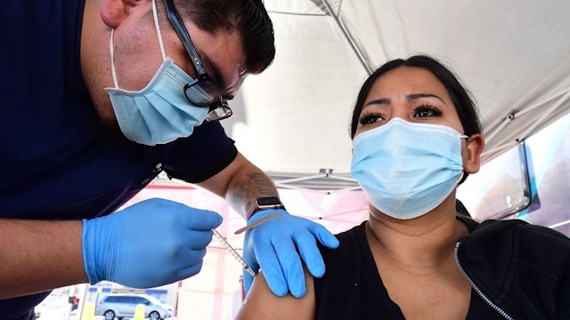 Carmen Penaloza receives her first dose of the Pfizer Covd-19 vaccine at a pop-up clinic offering vaccines and booster shots in Rosemead, California on November 29, 2021.