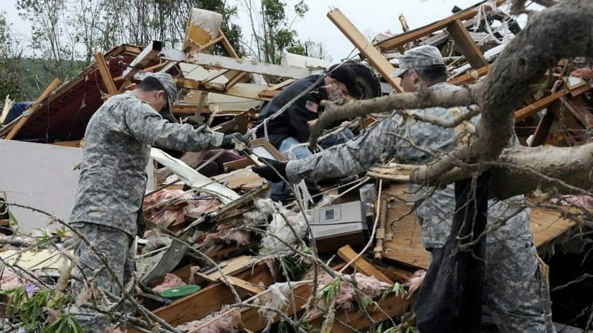 In this handout provided by the Arkansas National Guard, Arkansas National Guardsmen from the Conway based Special Troops Battalion, 39th Infantry Brigade Combat Team assist a family salvage heirlooms amongst the debris following a deadly tornado April 28, 2014 in Mayflower, Arkansas.