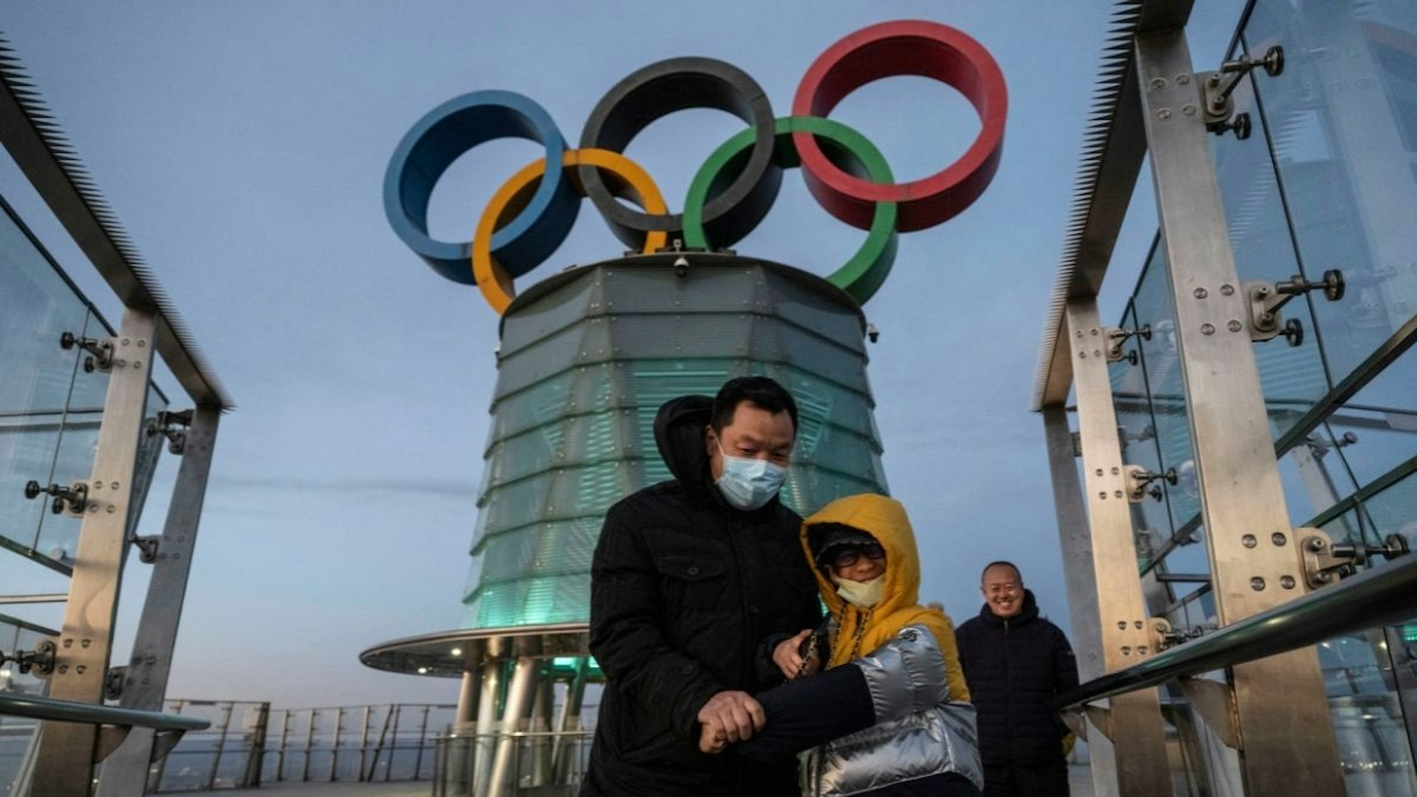 Visitors walk near a column with the Olympic Rings as they visit the top level of the Olympic Tower in the Olympic Green near the National Stadium, also known as the Bird's Nest, on December 11, 2021 in Beijing, China.