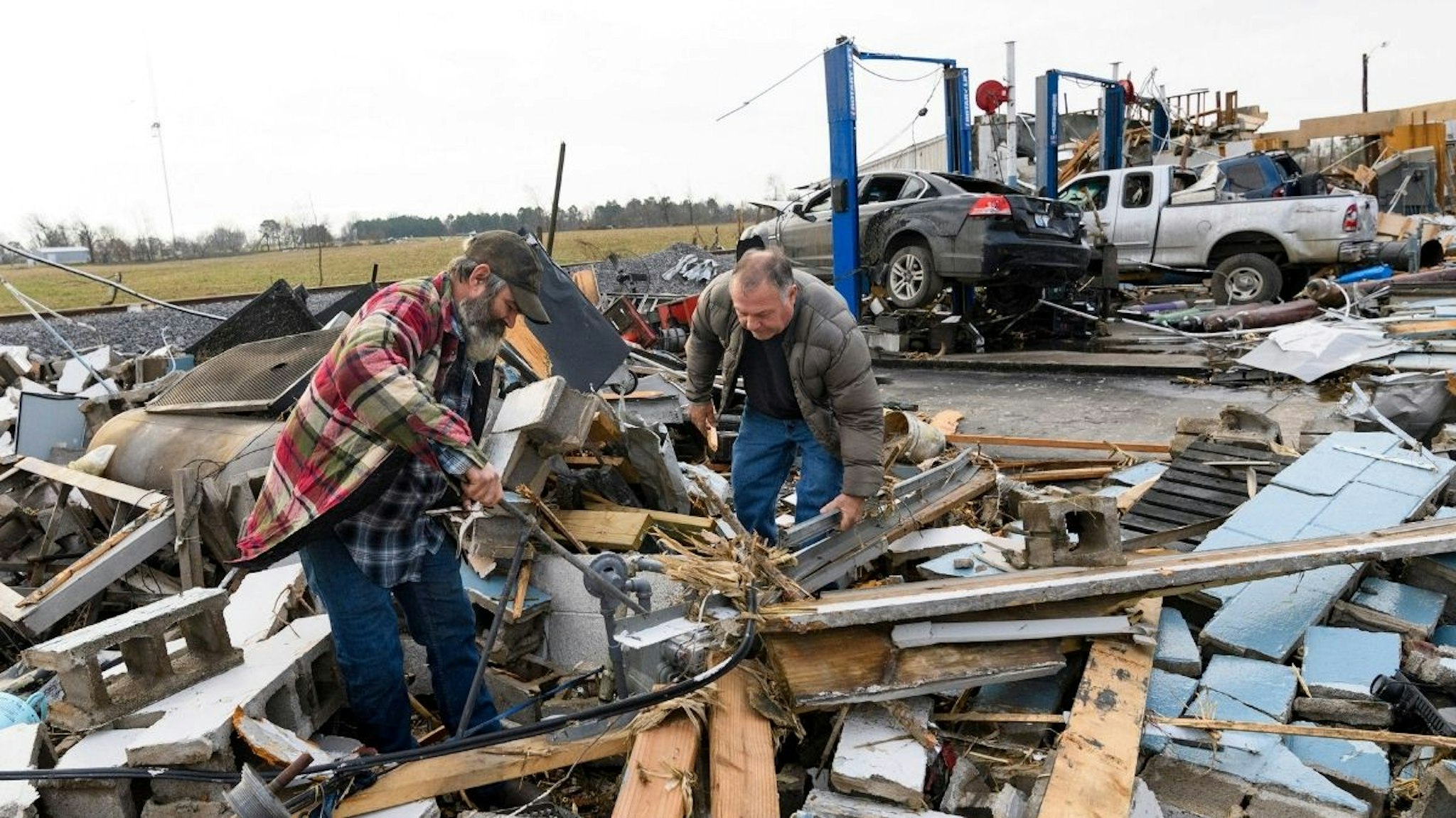 Martin Bolton (L) and shop owner Danny Wagner try to shut off a leaking gas meter after his automobile repair shop was destroyed by a tornado in Mayfield, Kentucky, on December 11, 2021.