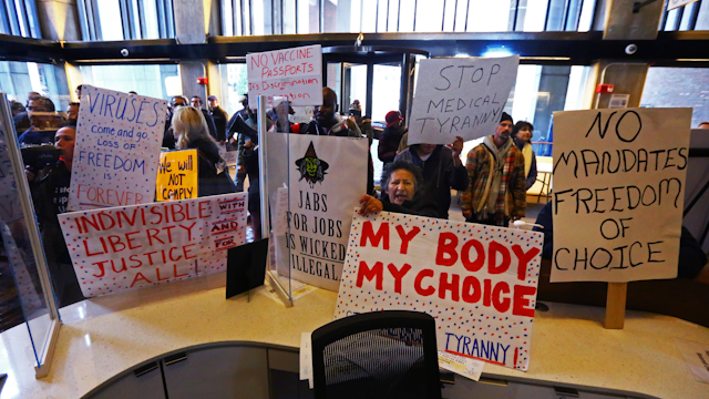 Protesters hold signs reading my body my choice, stop medical tyranny, and more, at Boston City Hall.