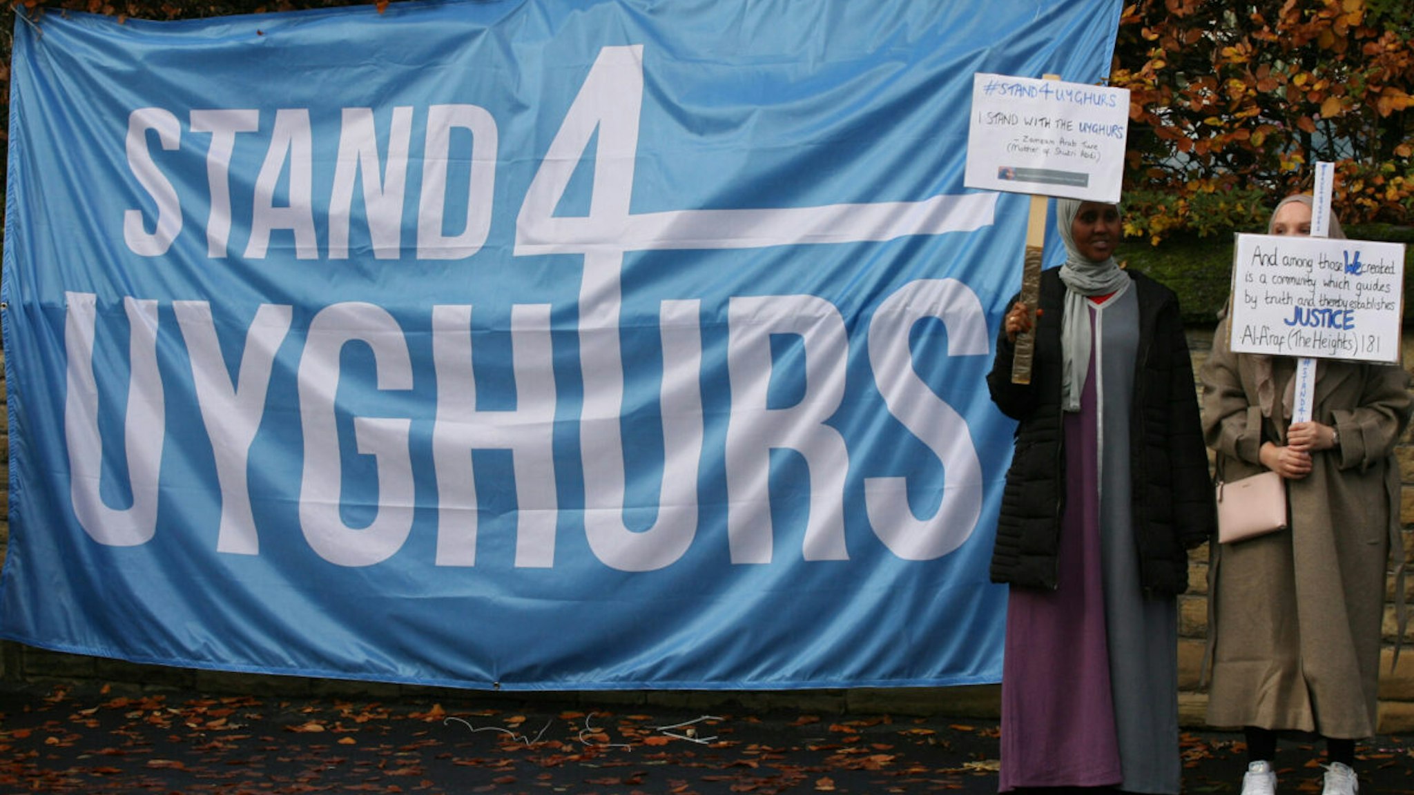 Two Muslim girls from Manchester's Muslim Community hold placards beside a Stand4Uyghurs banner, during the demonstration.