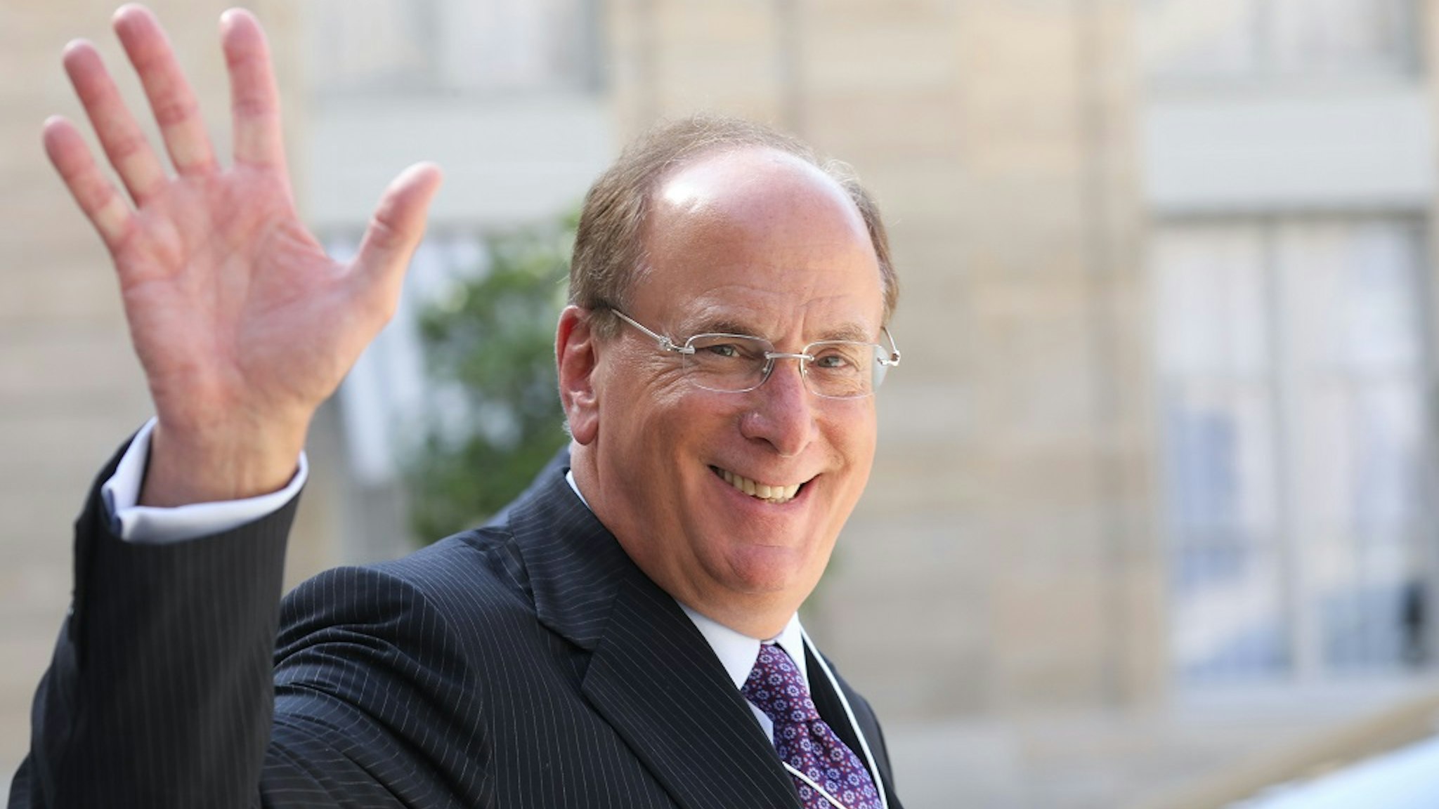 Chairman and CEO of BlackRock, Larry Fink (L) waves as he leaves a meeting about climate action investments with heads of sovereign wealth funds and French President at the Elysee Palace in Paris on July 10, 2019.