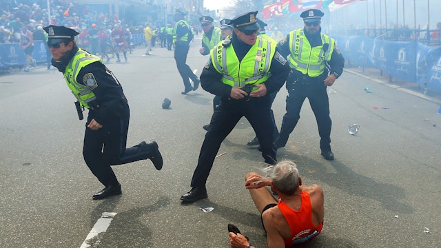 BOSTON - APRIL 15: Police officers with their guns drawn hear the second explosion down the street. The first explosion knocked down 78-year-old US marathon runner Bill Iffrig at the finish line of the 117th Boston Marathon.