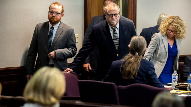 Greg McMichael, center, and his son, Travis McMichael, left, look at family members seated in the gallery when they walk into the courtroom for the reading of the jury's verdict of Greg McMichel and his son, Travis McMichael, and a neighbor, William "Roddie" Bryan in the Glynn County Courthouse on November 24, 2021 in Brunswick, Georgia.