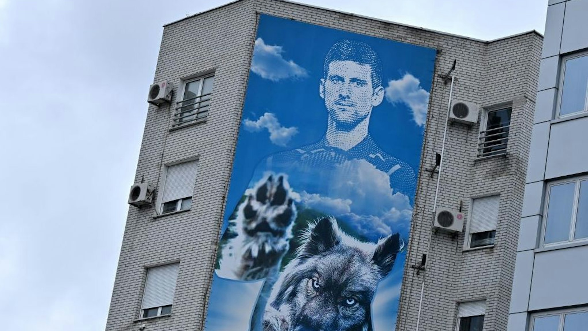A photograph taken on January 6, 2022 shows a billboard depicting Serbian tennis player Novak Djokovic displayed on the facade of a building, above his restaurant, in Belgrade. - The tennis world number one player is set to spend the night in an immigration detention facility in Australia, after winning a temporary reprieve in his deportation from Australia. The vaccine-sceptic Serb was detained having failed to "provide appropriate evidence" of double vaccination, or a medical exemption needed to enter the country. (Photo by Andrej ISAKOVIC / AFP) (Photo by ANDREJ ISAKOVIC/AFP via Getty Images)