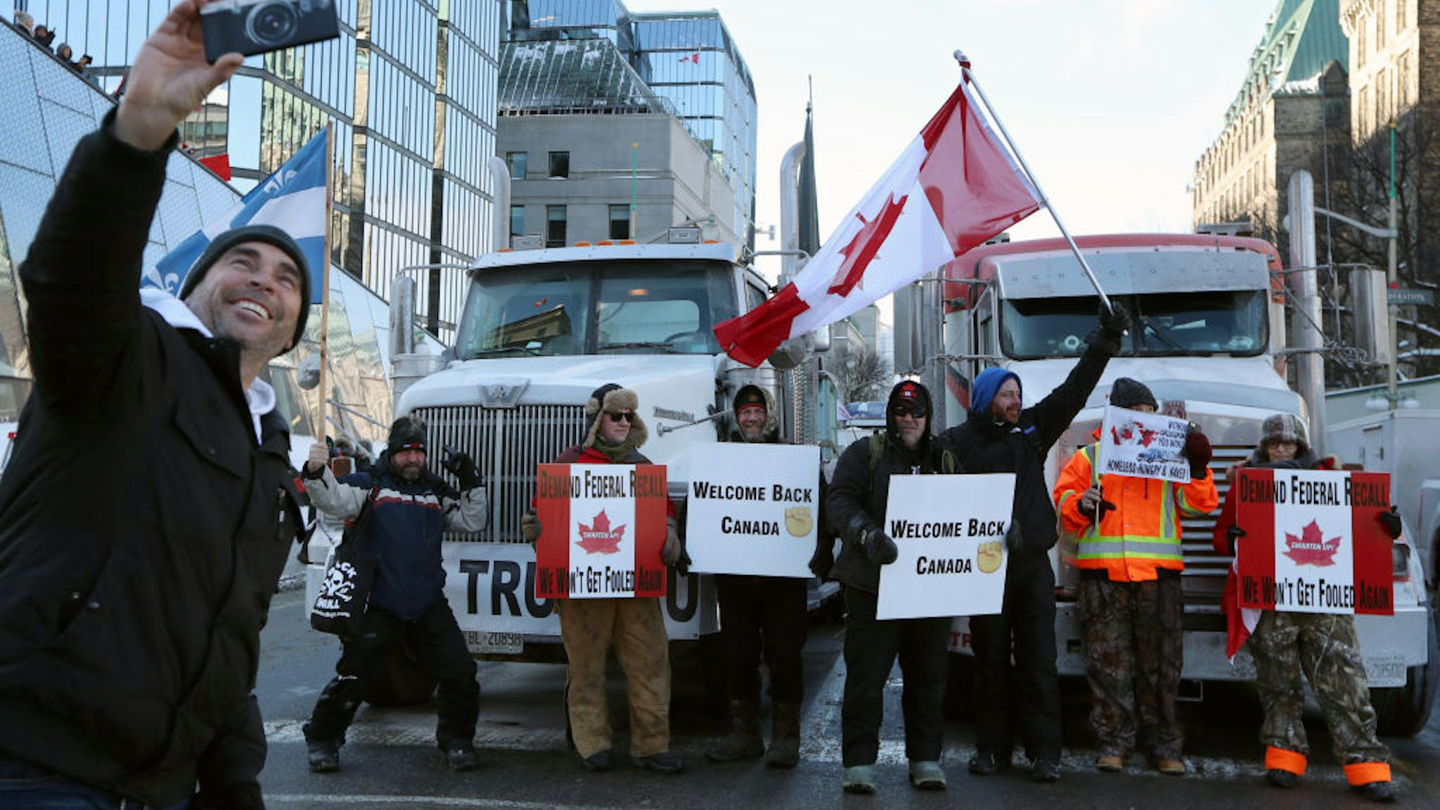 Demonstrators take photos with trucks parked on Wellington Street during a protest near Parliament Hill in Ottawa, Ontario, Canada, on Saturday, Jan. 29, 2022. A convoy of truckers and others who oppose vaccine mandates began rolling into Ottawa on Friday, putting Canada's capital city on edge amid warnings from police that they dont know how large the protests will get. Photographer: David Kawai/Bloomberg via Getty Images
