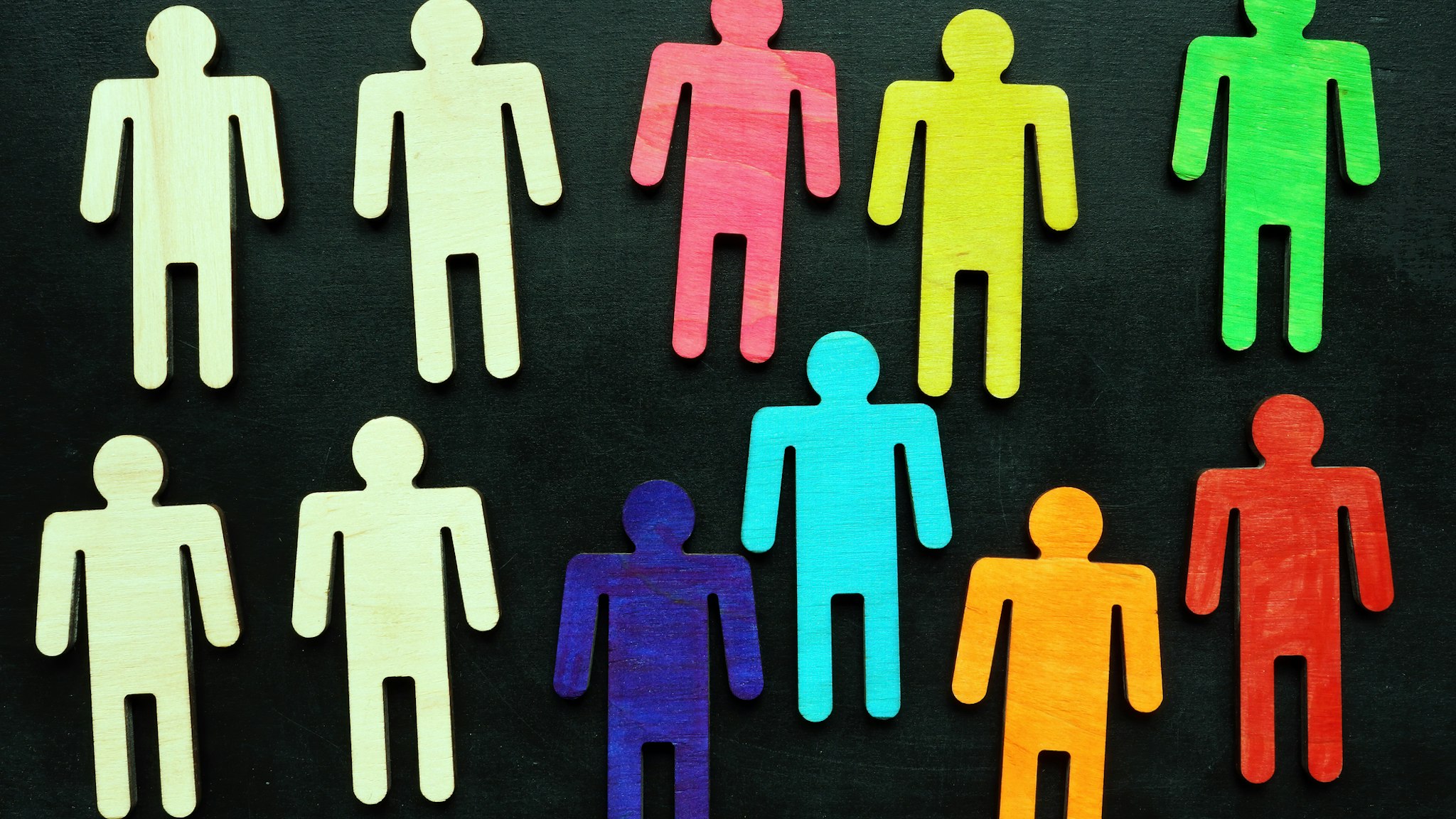 Equality and diversity concept. Multi-colored wooden figurines on a blackboard.