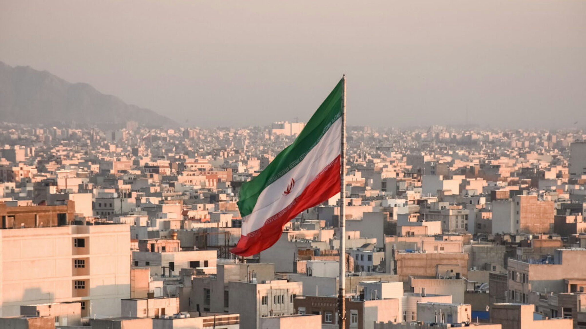 Iranian flag waving with cityscape on background in Tehran, Iran