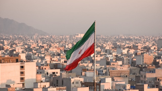 Iranian flag waving with cityscape on background in Tehran, Iran