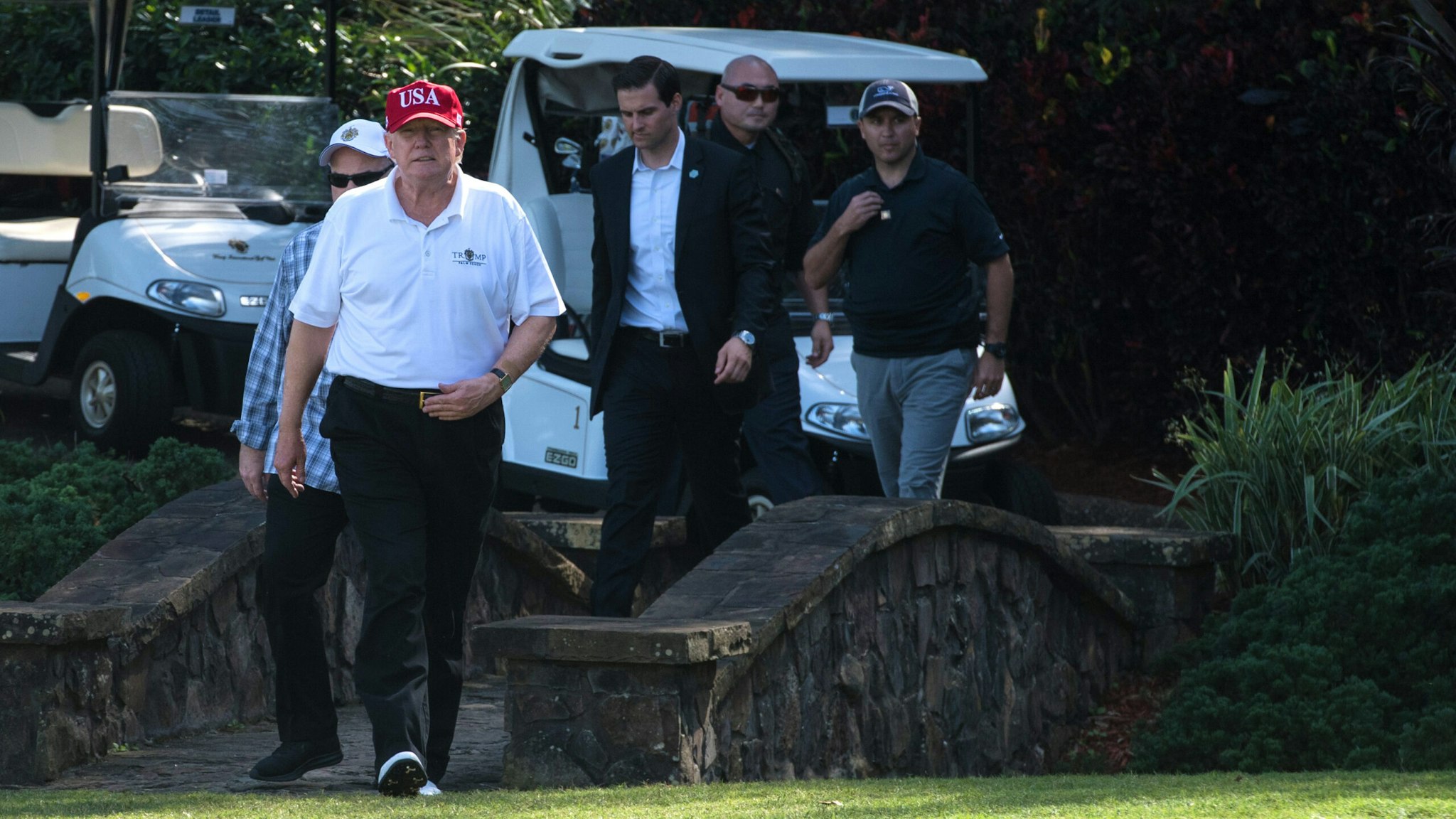 US President Donald Trump walks onto the green at the Trump International Golf Course in Mar-a-Lago, Florida during an invitation for United States Coast Guard service members to play golf on December 29, 2017. The President invited members of the Coast Guard to play golf to thank them personally for their service of patrolling the waters near Palm Beach and Mar-a-Lago.