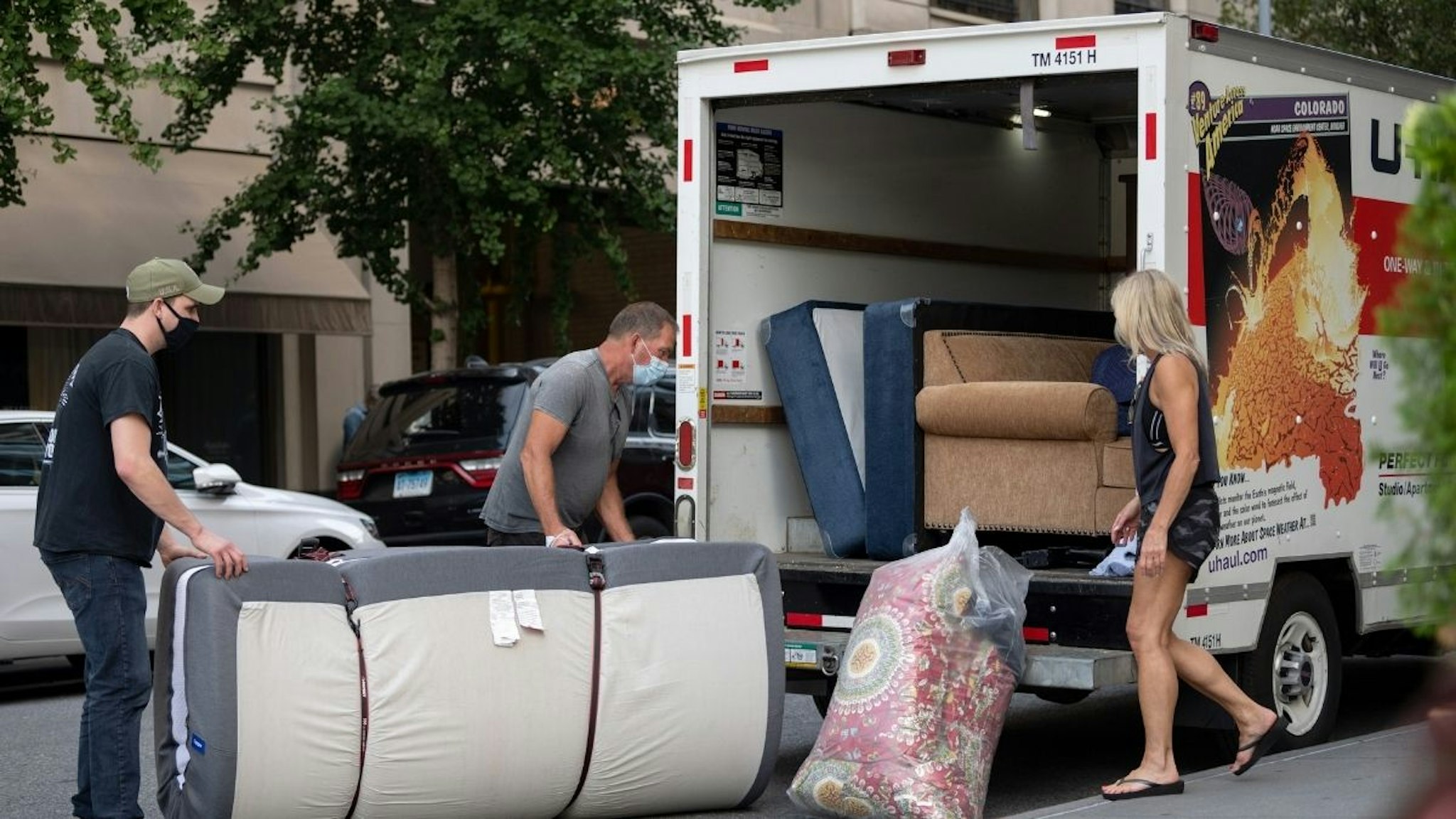 People wearing masks load furniture into a U-haul moving truck as the city continues Phase 4 of re-opening following restrictions imposed to slow the spread of coronavirus on September 12, 2020 in New York City.