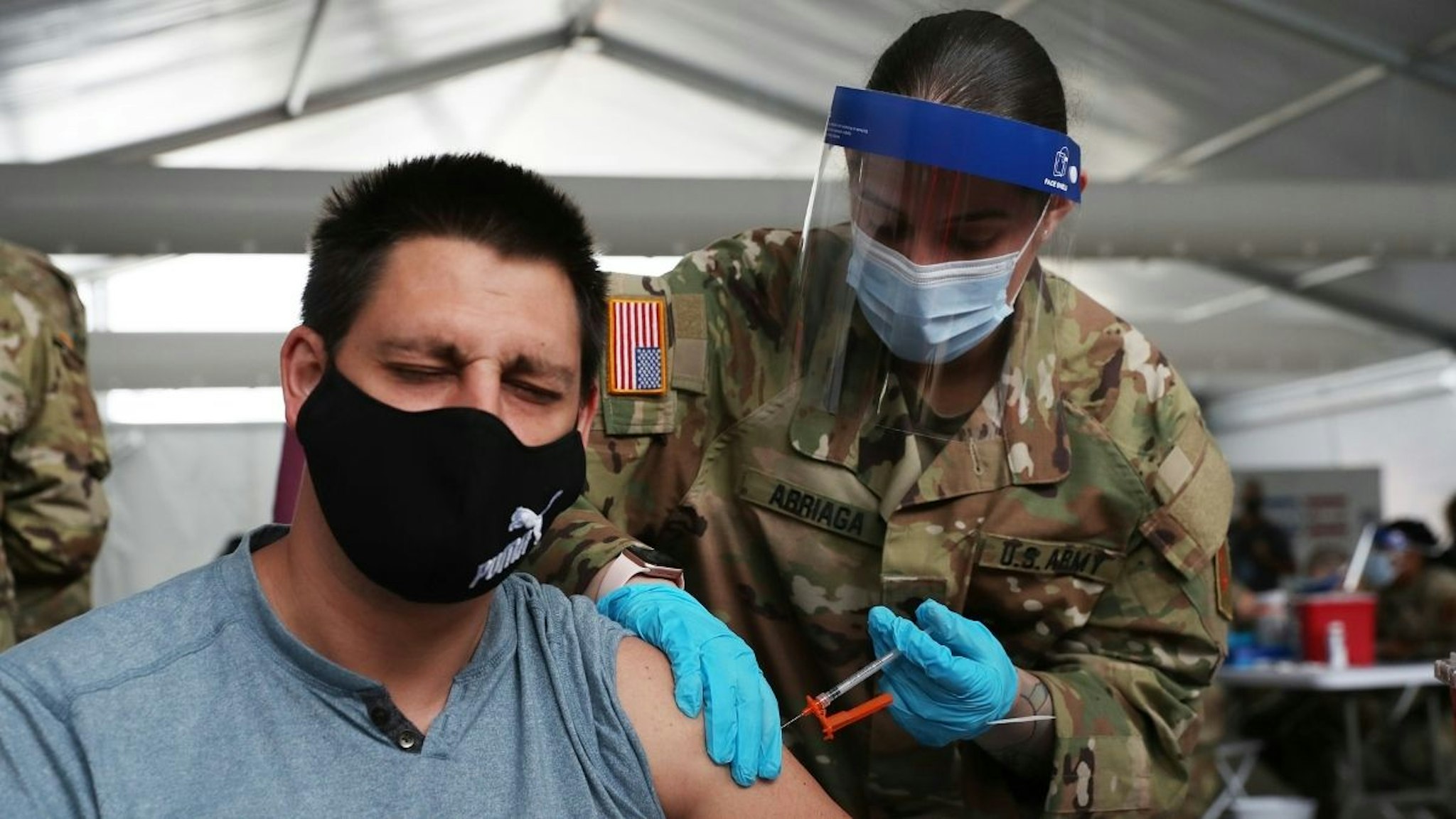 A U.S. Army soldier from the 2nd Armored Brigade Combat Team, 1st Infantry Division, immunizes Max Pietro with the Johnson and Johnson COVID-19 vaccine at the Miami Dade College North Campus on March 10, 2021 in North Miami, Florida.