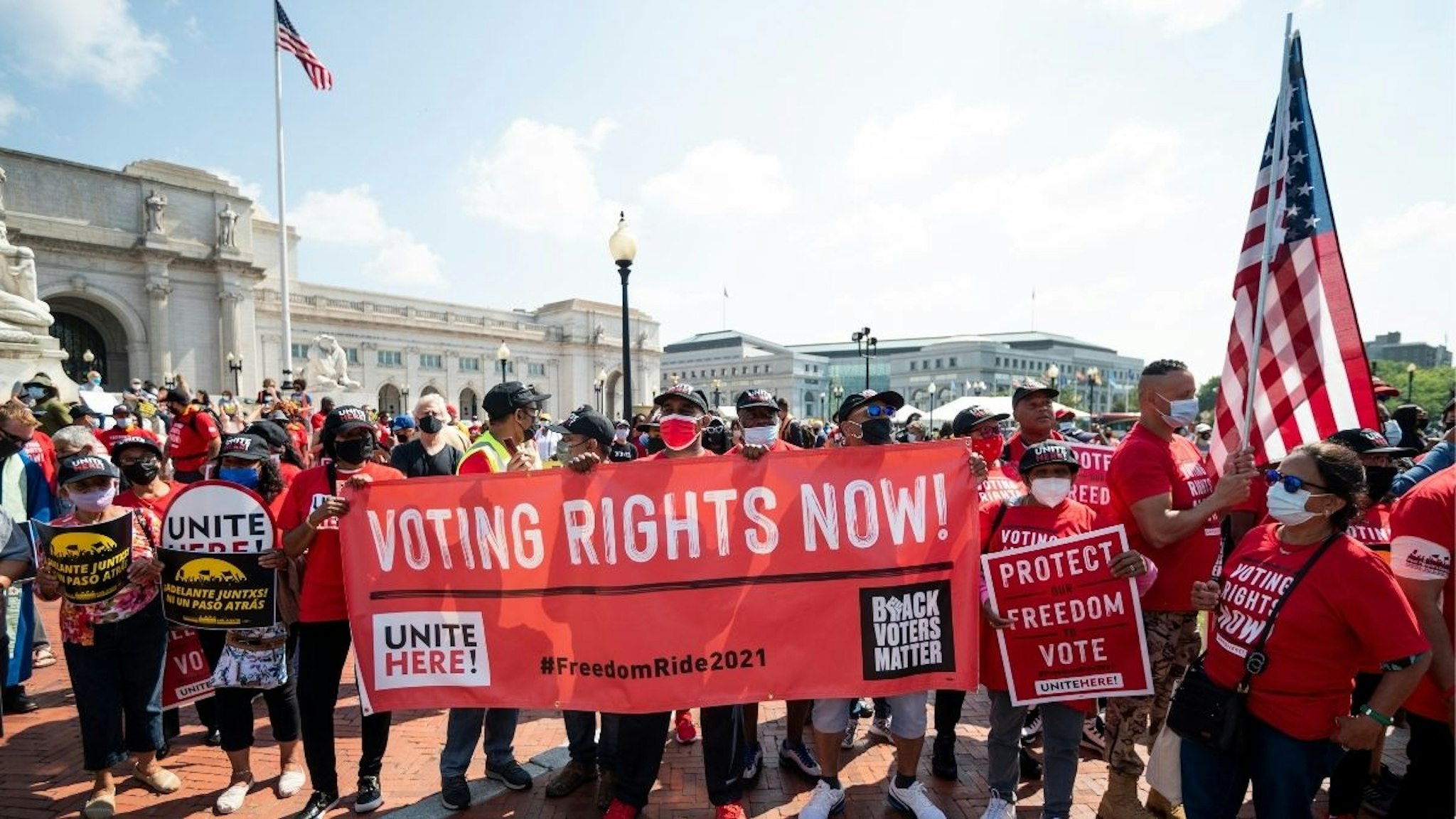 Rally attendees hold signs outside of Union Station in Washington as the Poor Peoples Campaign and the Unite union hold a rally and march to protest voter suppression laws on Monday, Aug. 2, 2021.