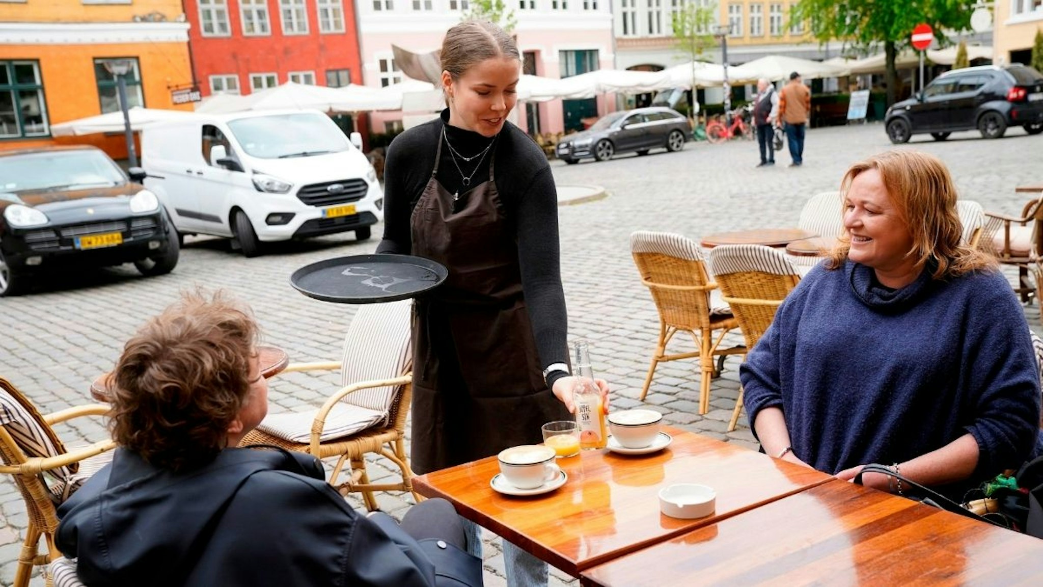 People sit at the terrasse of the Huks Fluks restaurant after it reopened at Graabroedre Square in Copenhagen on May 18, 2020.