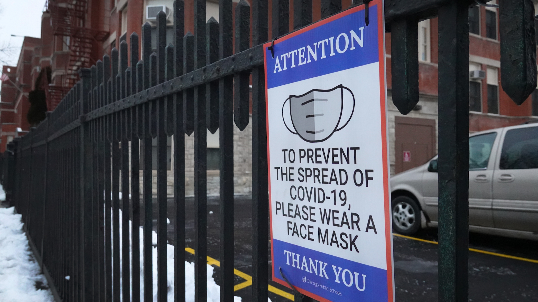 sign on the fence outside of Lowell elementary school asks students, staff and visitors to wear a mask to prevent the spread of COVID-19 on January 05, 2022 in Chicago, Illinois.