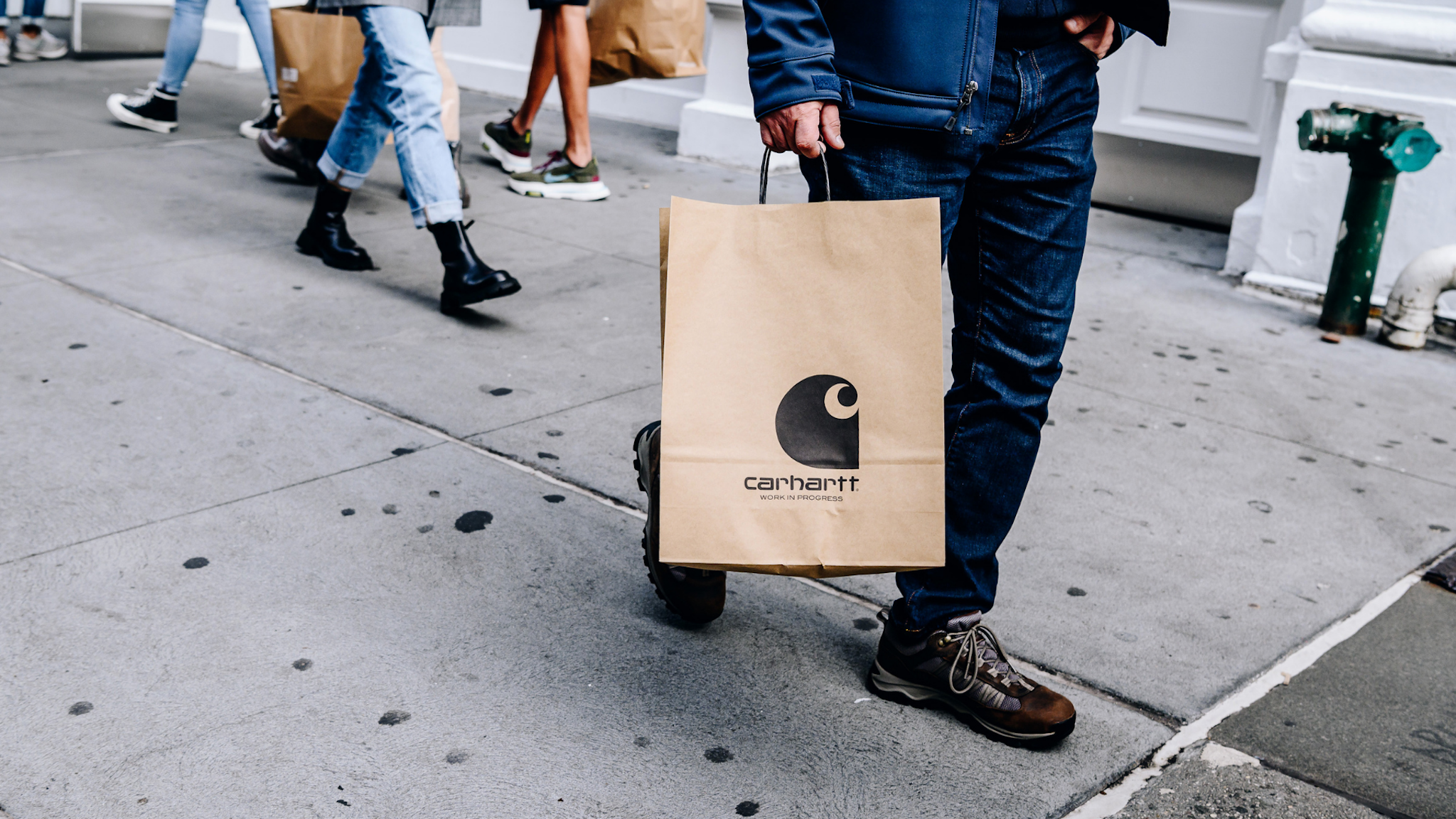 A pedestrian carries a Carhartt shopping bag in the SoHo neighborhood of New York, U.S., on Sunday, Oct. 24, 2021. Consumers are facing dire warnings to get their holiday shopping done early this year, especially if theyre planning to do it online. Bottlenecks in the global supply chain are posing a new challenge to the e-commerce industry, and out-of-stock items represent a growing concern.