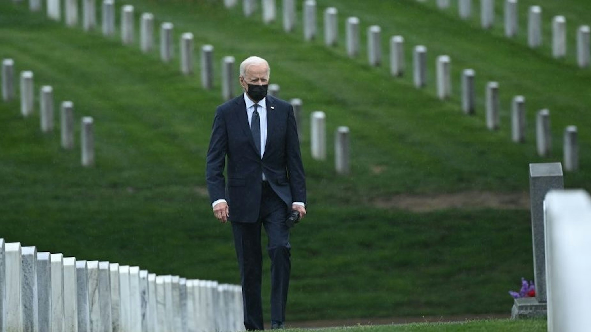 US President Joe Biden walks through Arlington National cemetary to honor fallen veterans of Afghan conflict in Arlington, Virginia on April 14, 2021. - President Joe Biden announced it's "time to end" America's longest war with the unconditional withdrawal of troops from Afghanistan, where they have spent two decades in a bloody, largely fruitless battle against the Taliban. (Photo by Brendan SMIALOWSKI / AFP) (Photo by