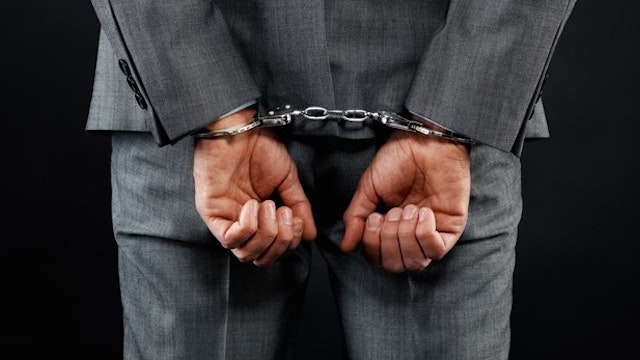 Rear view of man in suit wearing handcuffs