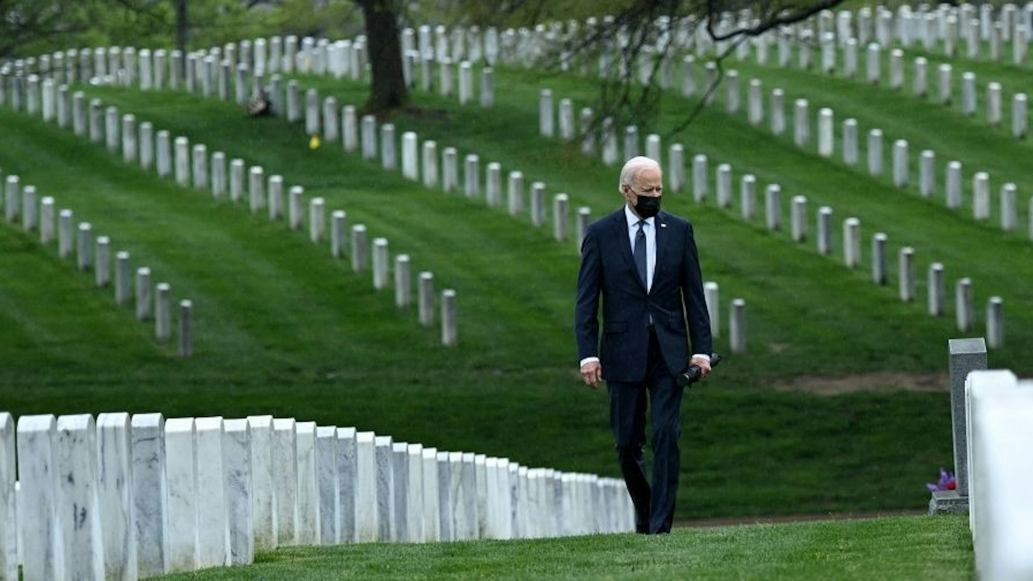 TOPSHOT - US President Joe Biden walks through Arlington National cemetary to honor fallen veterans of the Afghan conflict in Arlington, Virginia on April 14, 2021. - President Joe Biden announced it's "time to end" America's longest war with the unconditional withdrawal of troops from Afghanistan, where they have spent two decades in a bloody, largely fruitless battle against the Taliban. (Photo by Brendan SMIALOWSKI / AFP) (Photo by