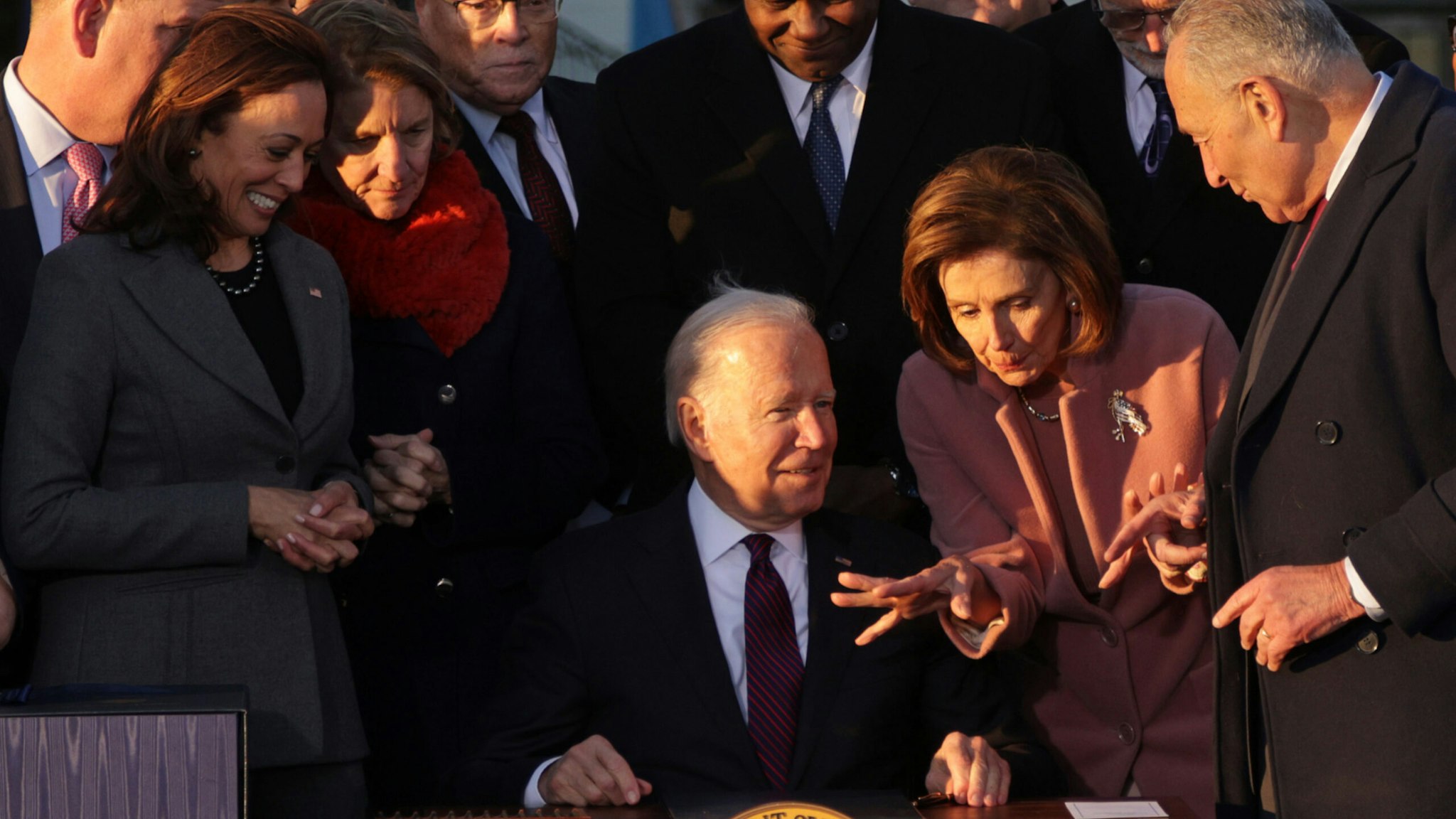 U.S. President Joe Biden (3rd-R) talks to Speaker of the House Rep. Nancy Pelosi (D-CA) (2nd-R) as Senate Majority Leader Sen. Chuck Schumer (D-NY) (R) and Vice President Kamala Harris (L) look on after signing the Infrastructure Investment and Jobs Act as he is surrounded by lawmakers and members of his Cabinet during a ceremony on the South Lawn at the White House on November 15, 2021 in Washington, DC.