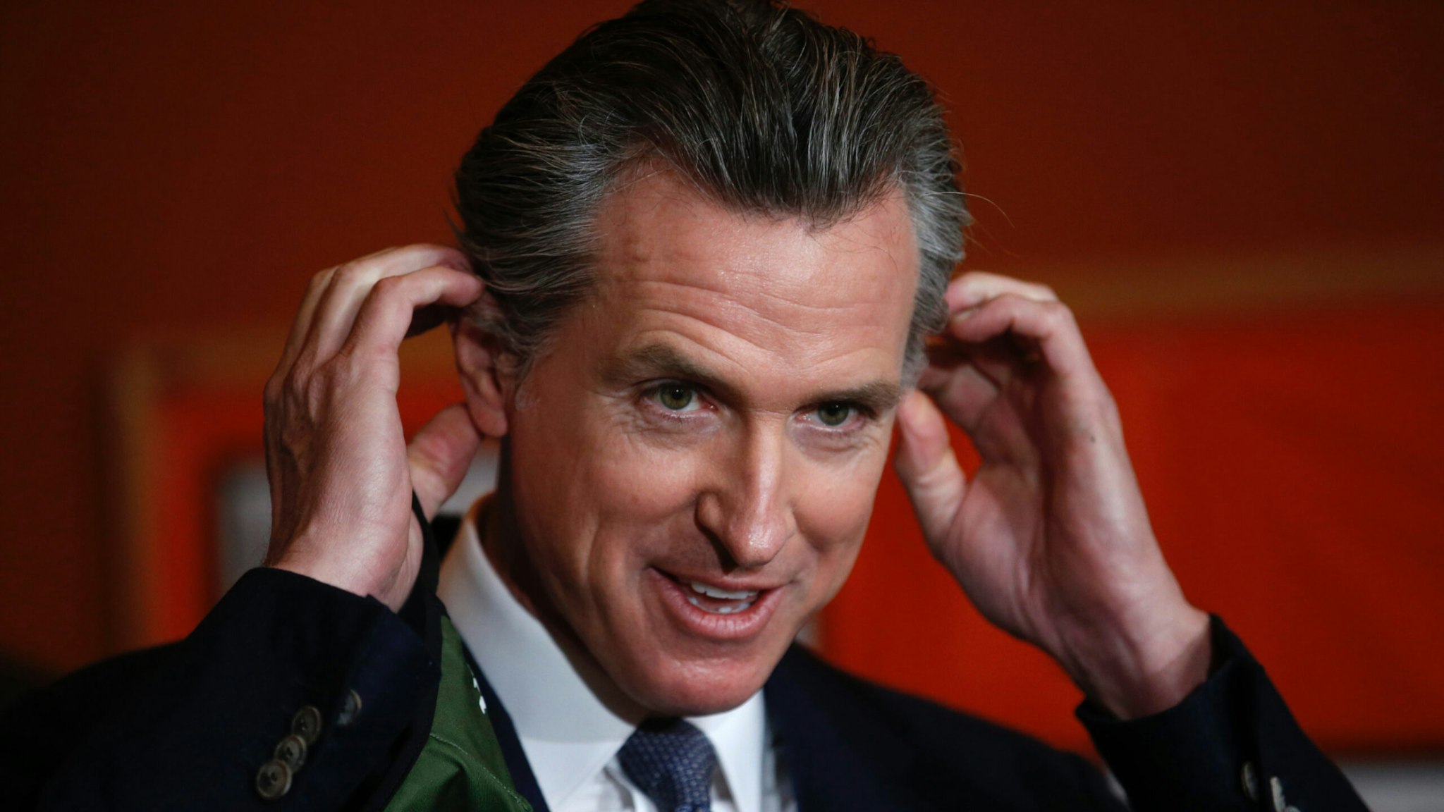 Gov. Gavin Newsom removes his mask before speaking during a press conference at at the Native American Health Center in Oakland, Calif., on Wednesday, Dec. 22, 2021.
